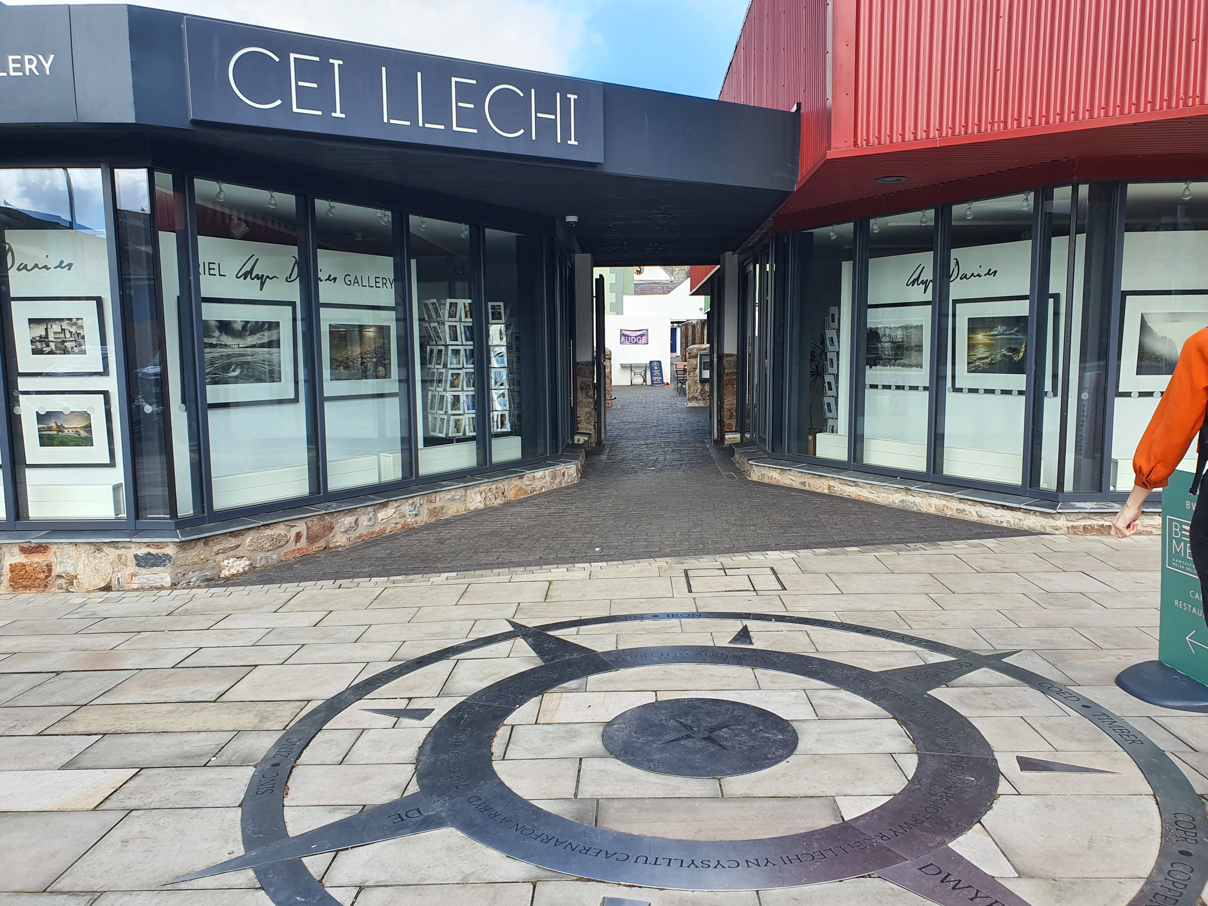 A storefront with large windows displaying photographs. There is a compass in the foreground.