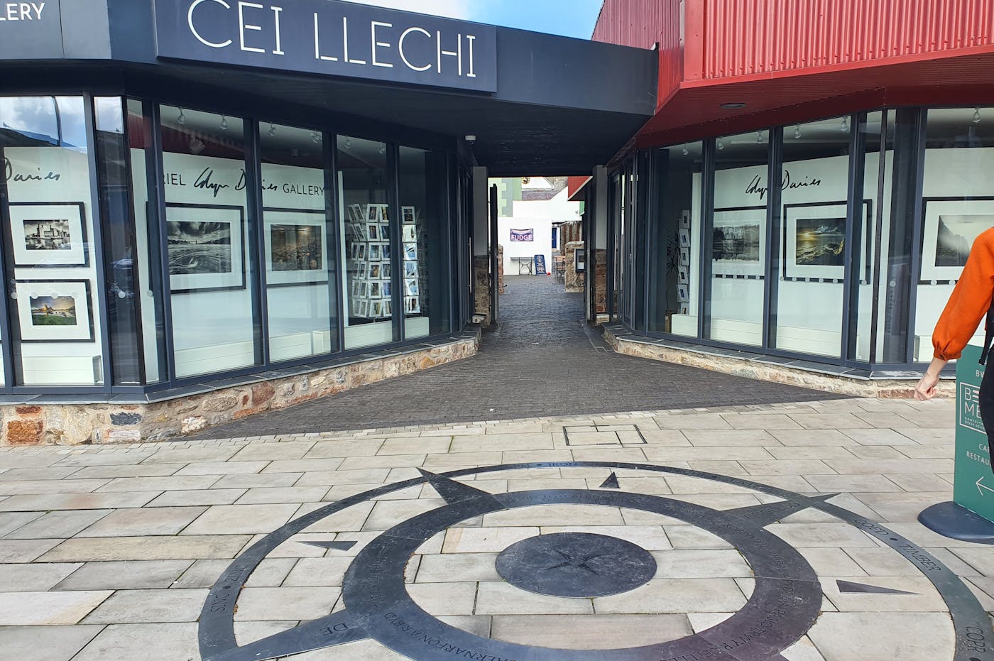 A storefront with large windows displaying photographs. There is a compass in the foreground.
