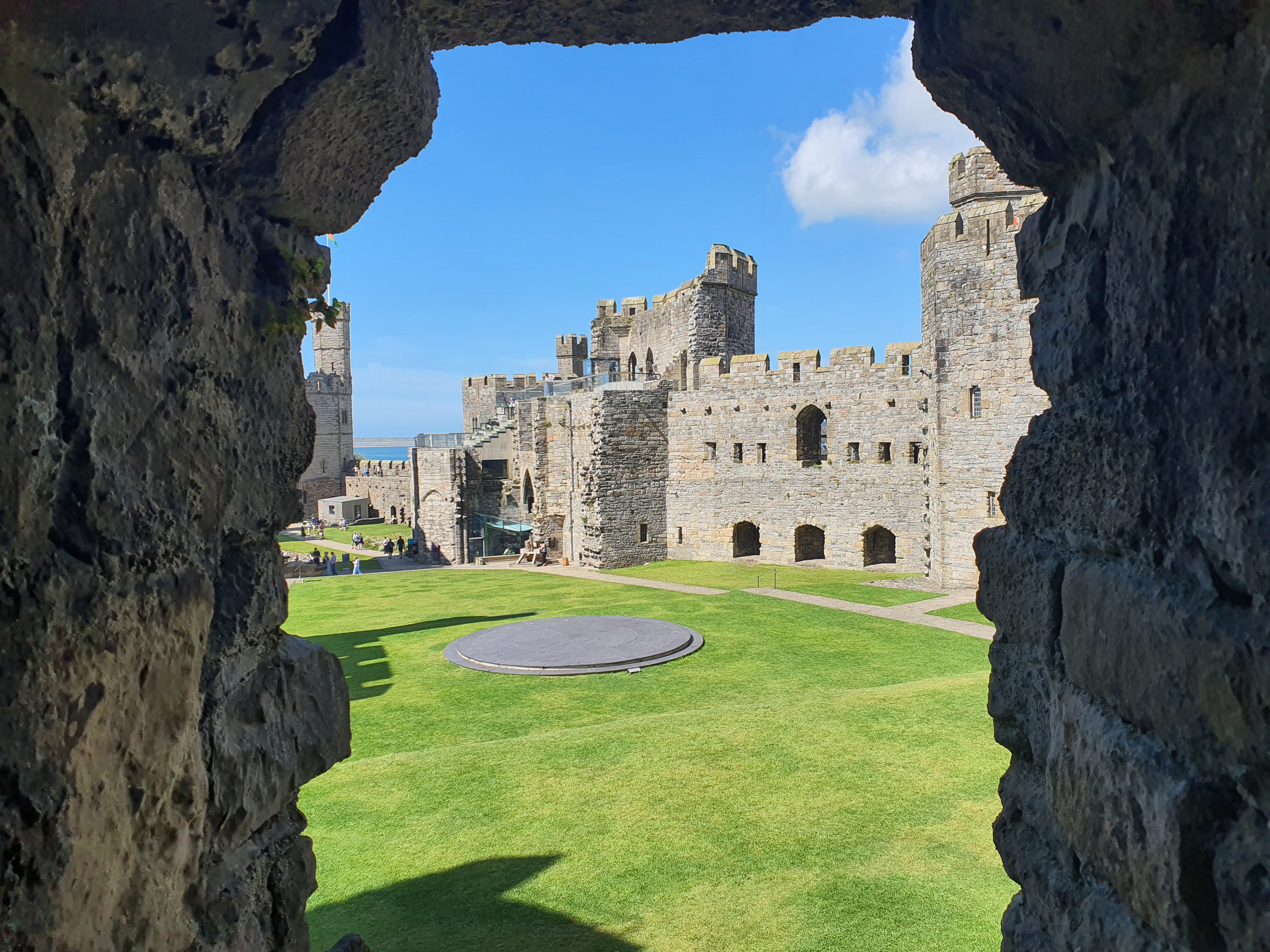 A view of a castle courtyard through a narrow window.