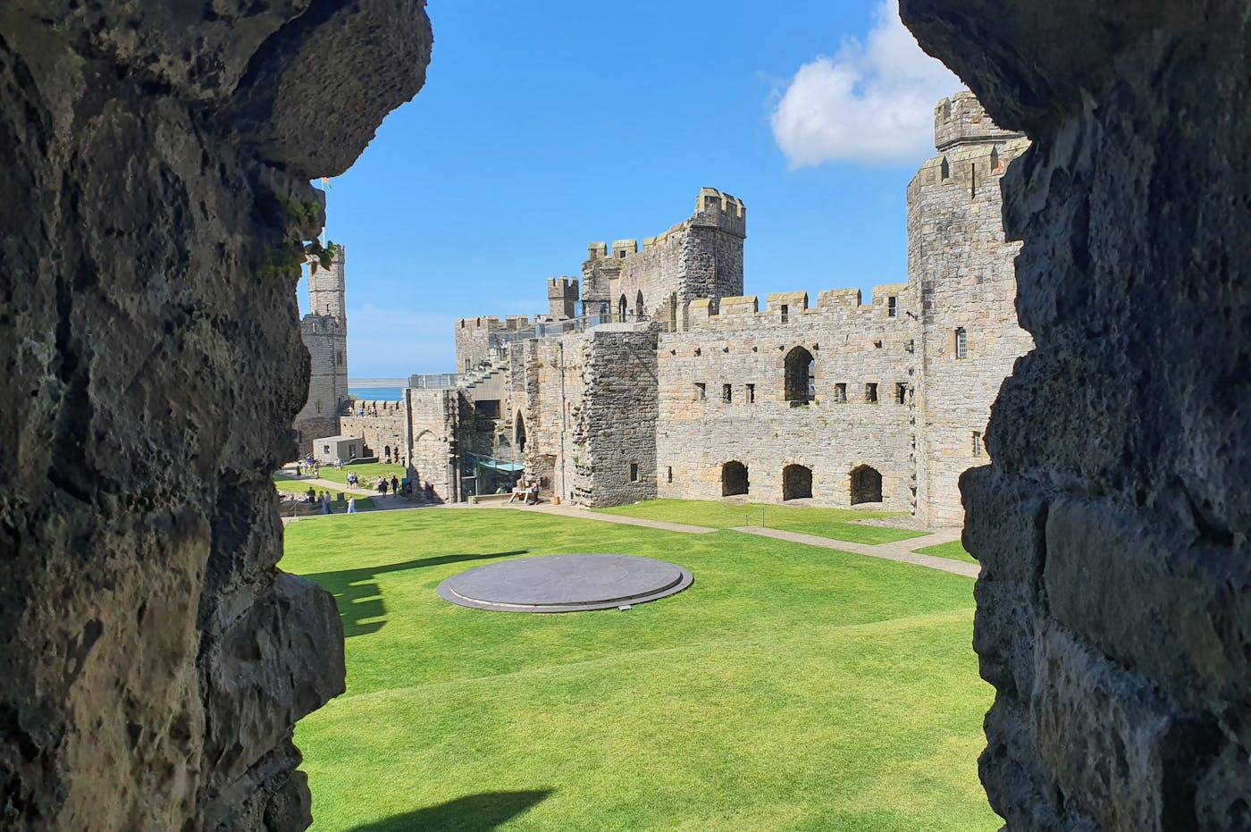A view of a castle courtyard through a narrow window.