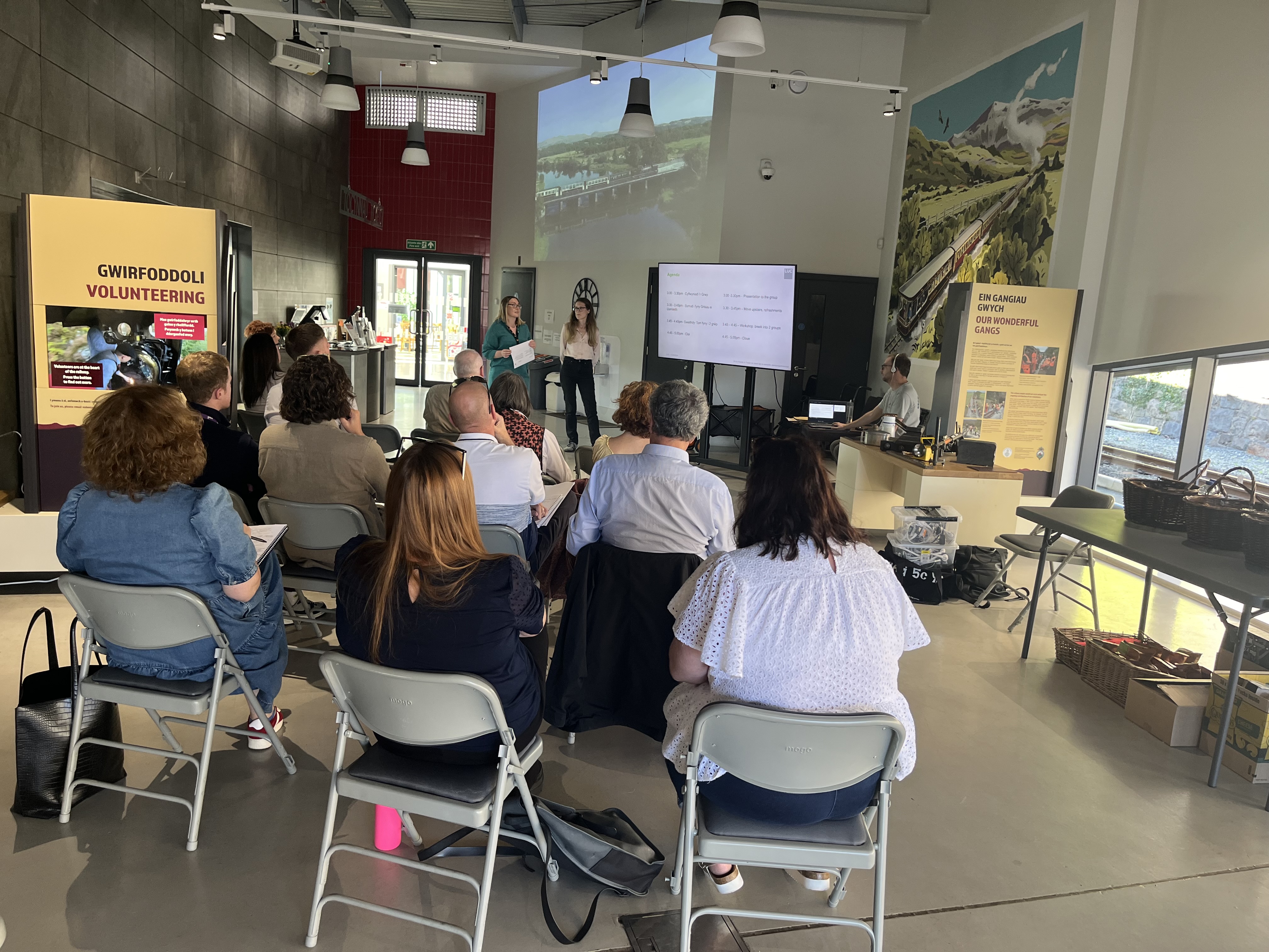 A group of people sat in a community hall listening to a presentation.