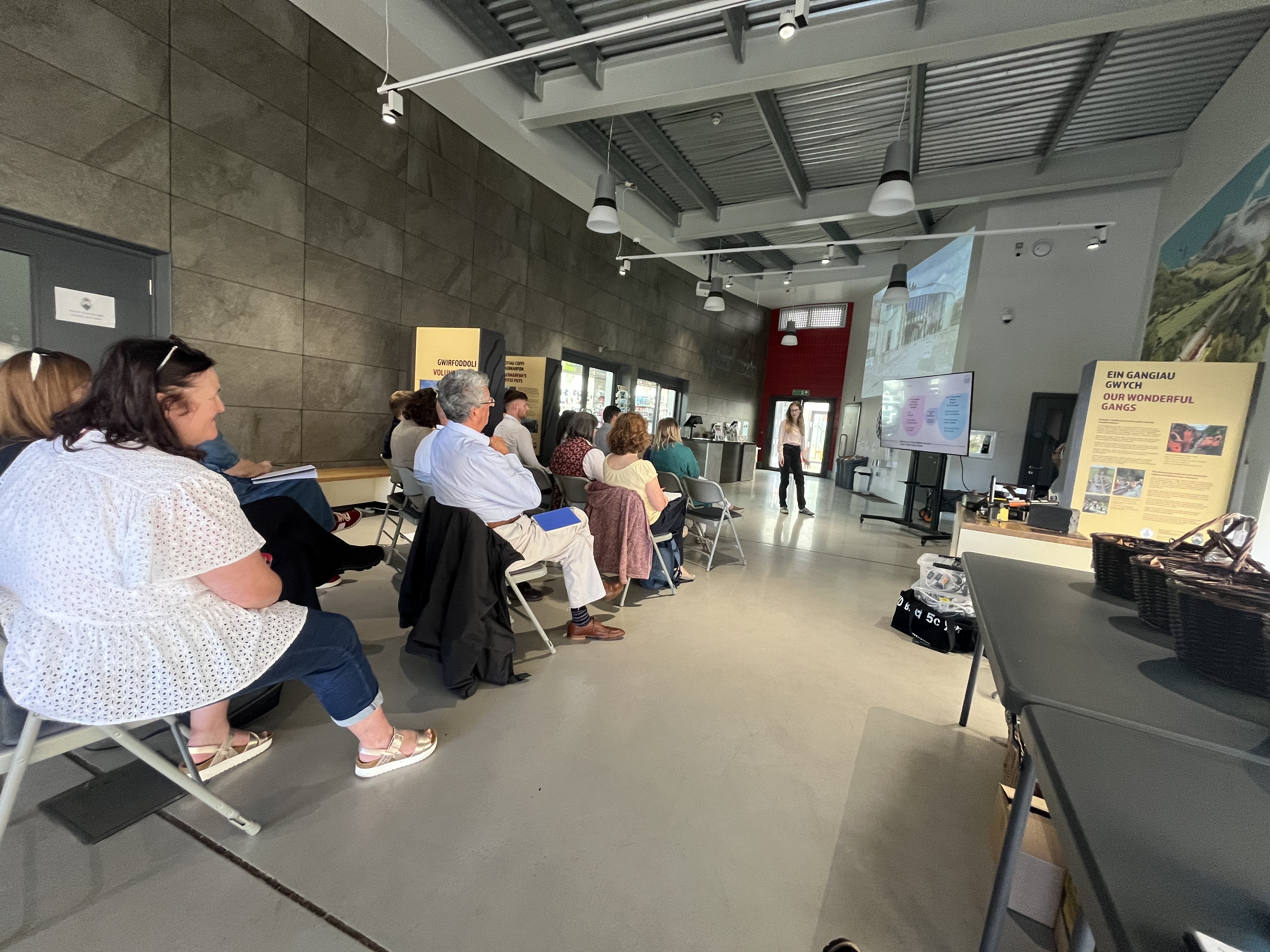 A group of people sat in a community hall listening to a presentation.