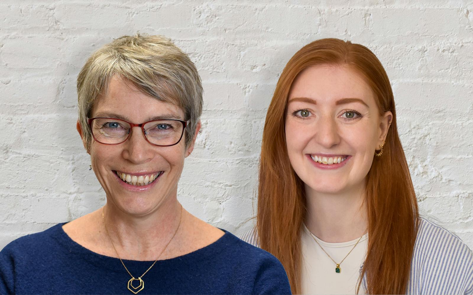 Two people in front of white brick wall;