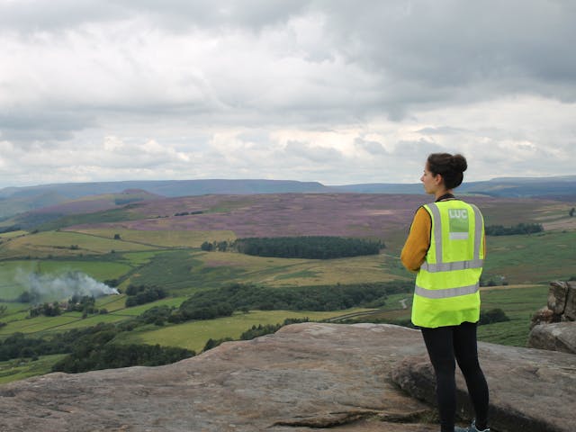 Person looking over hills, wearing hi-vis vest