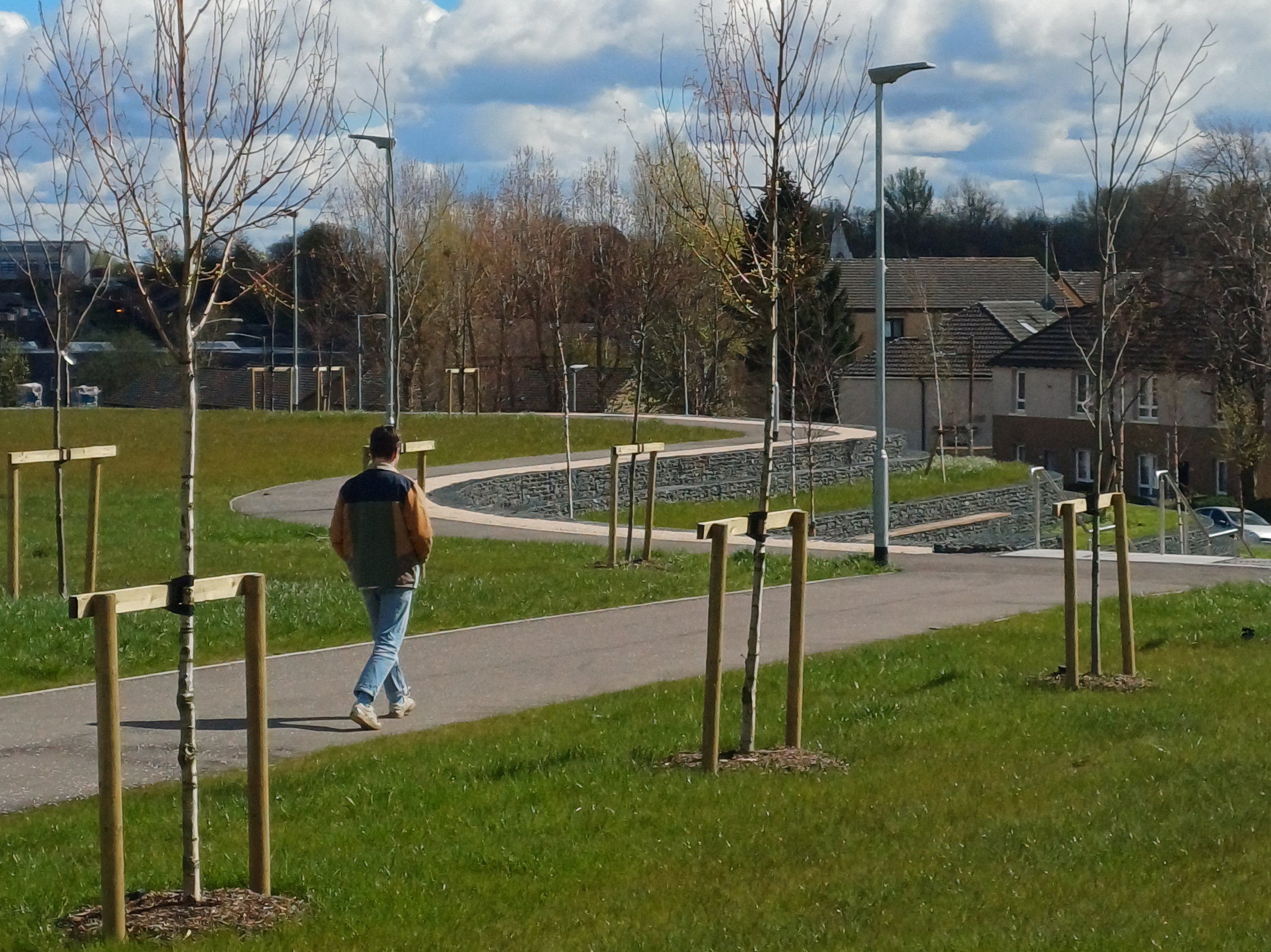 a man walking in a grassy and sunny park