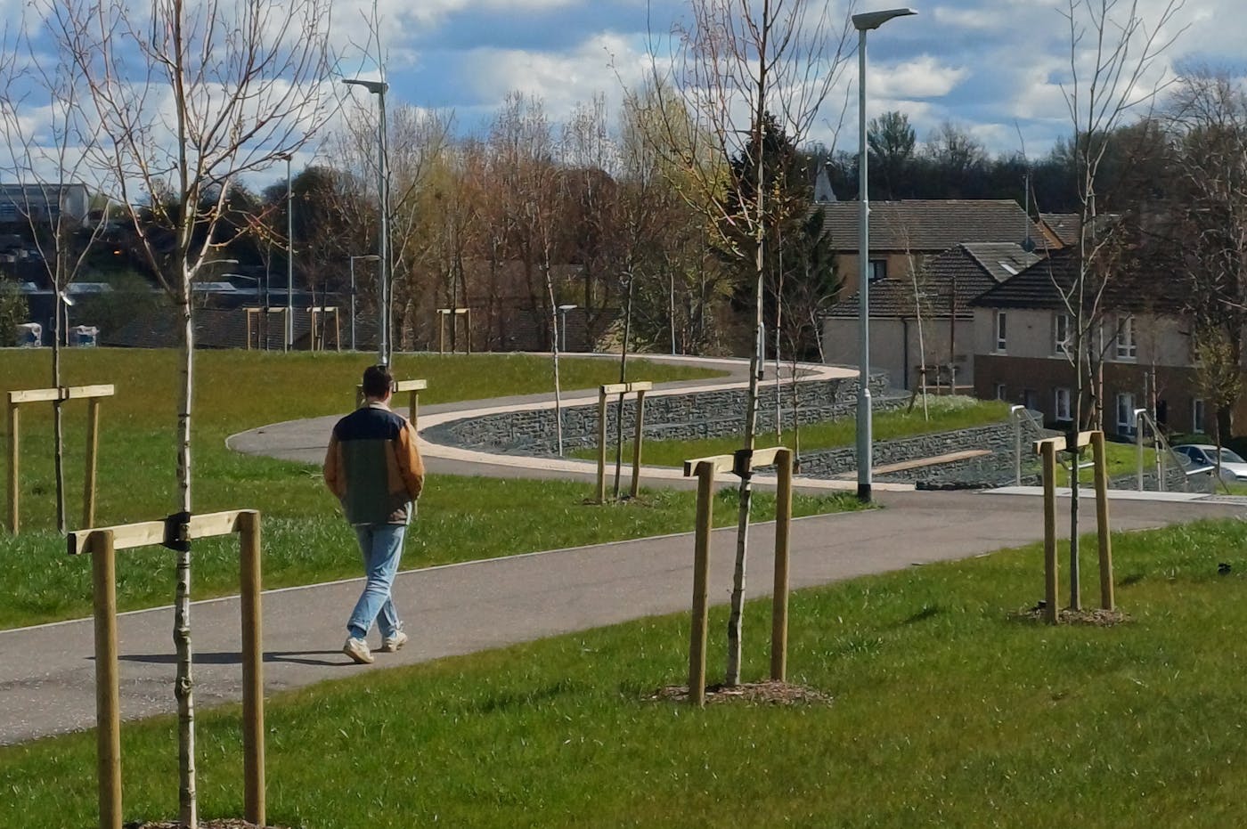 a man walking in a grassy and sunny park