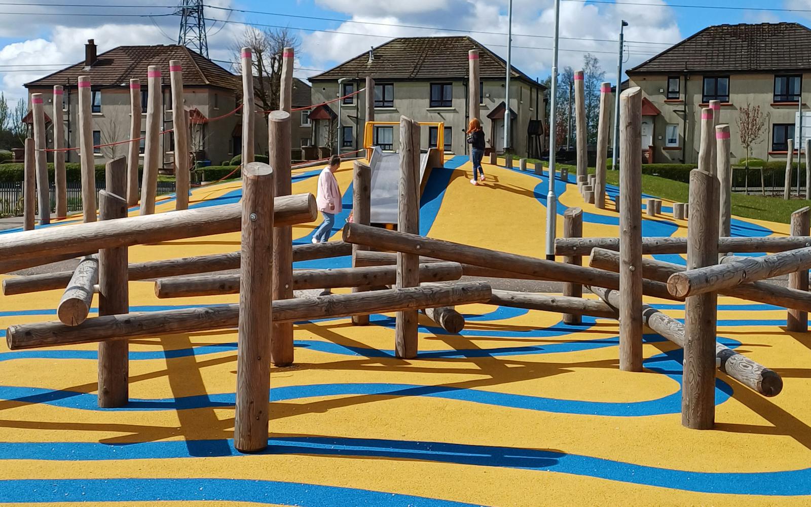 a yellow and blue playground with wooden pillars
