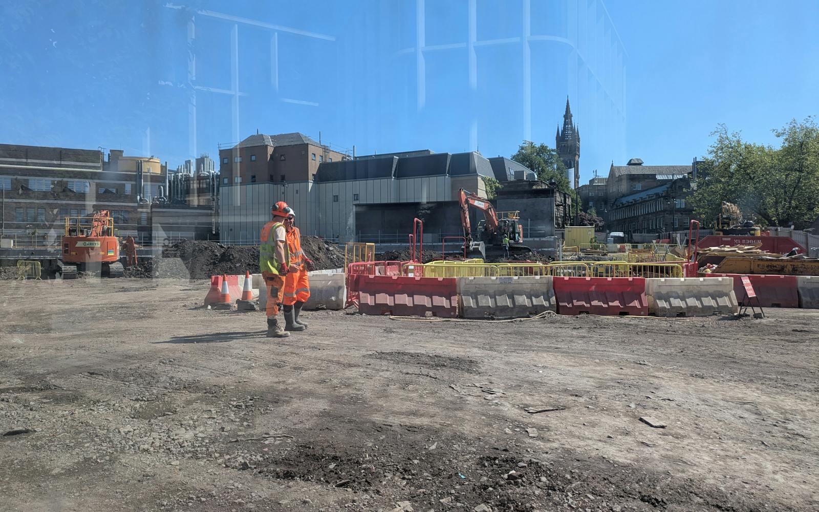 two workers standing on a construction site under a clear sky.
