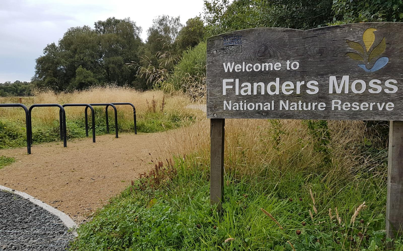 A sign that says Flanders Moss next to a path