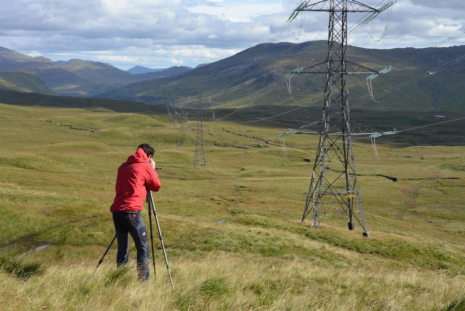 a man standing in a field using a camera to take photos of his surroundings