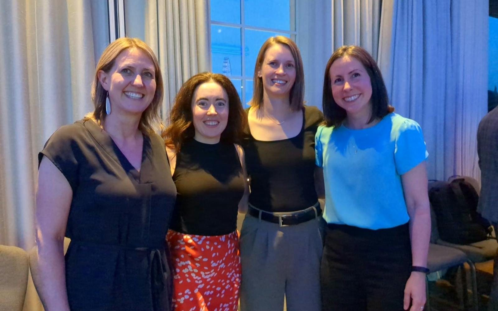 Four people stood in a line smiling at the camera
