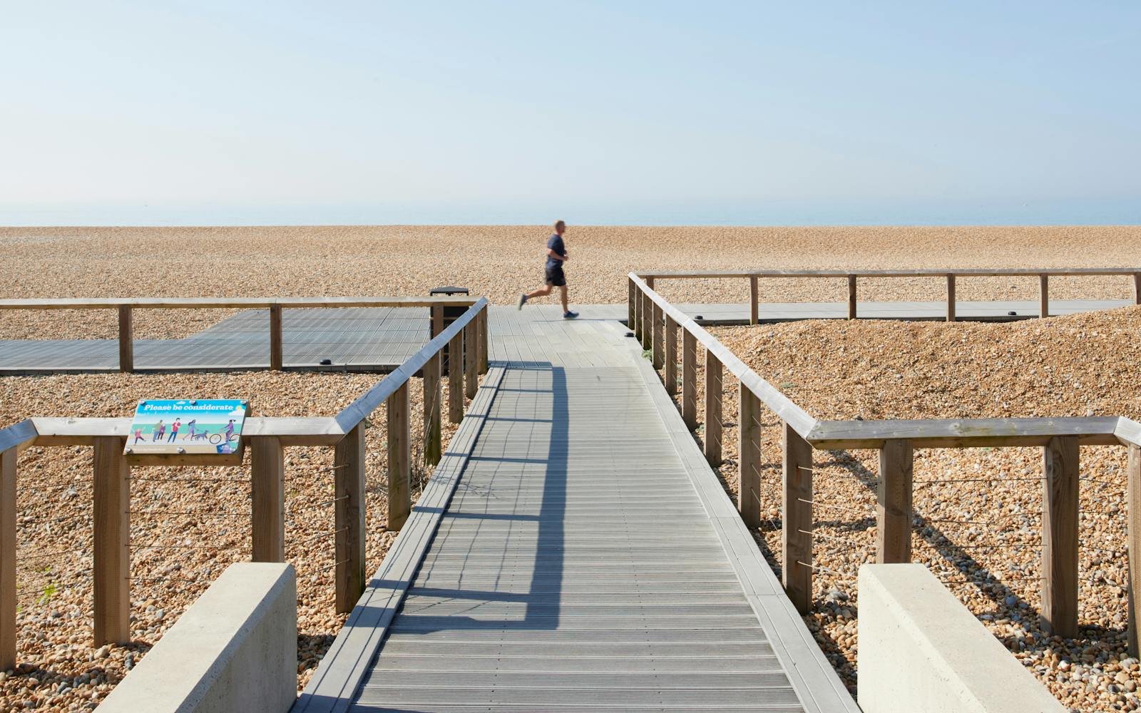 A wide shot of the revitalised Black Rock seafront in Brighton, showing a new boardwalk and a pebble beach on a sunny day.