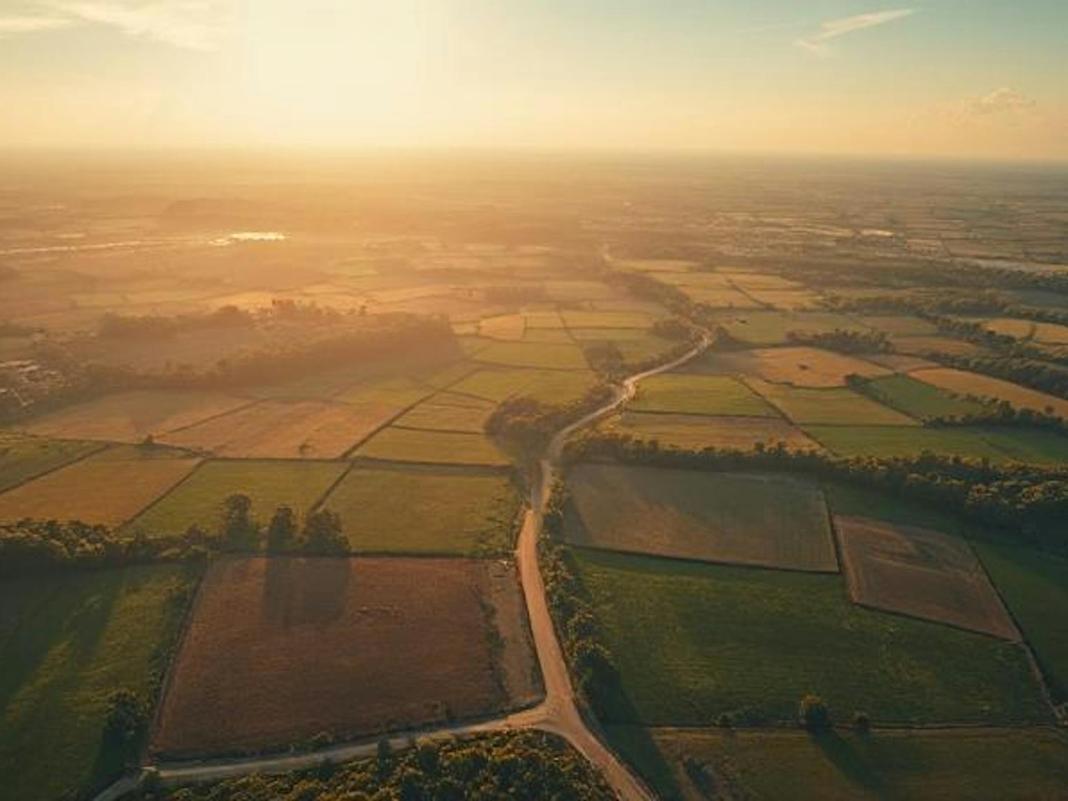 A landscape of fields with a sunset in the background