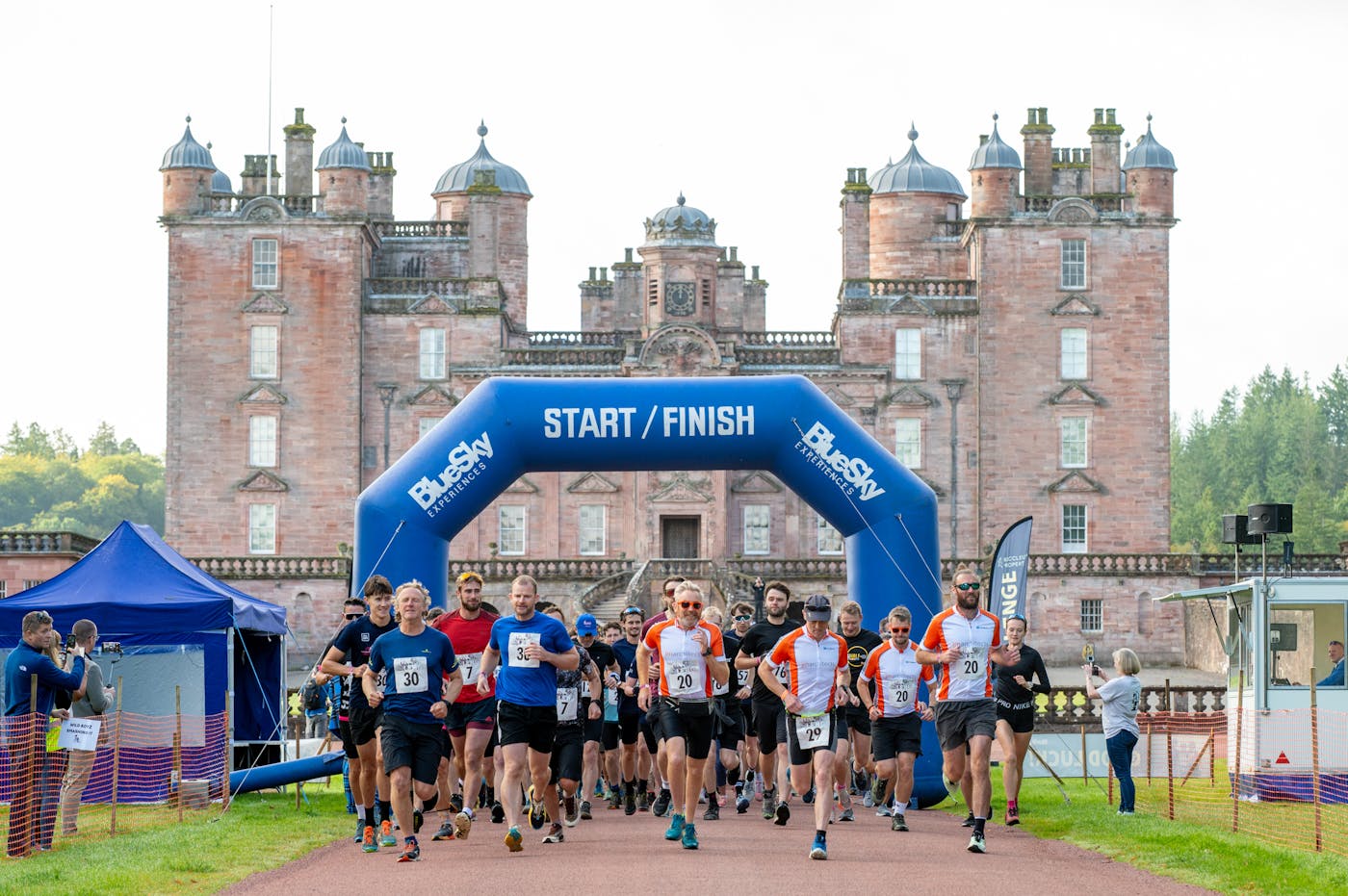 A group of people in sports gear at the start of a race with a castle in the background