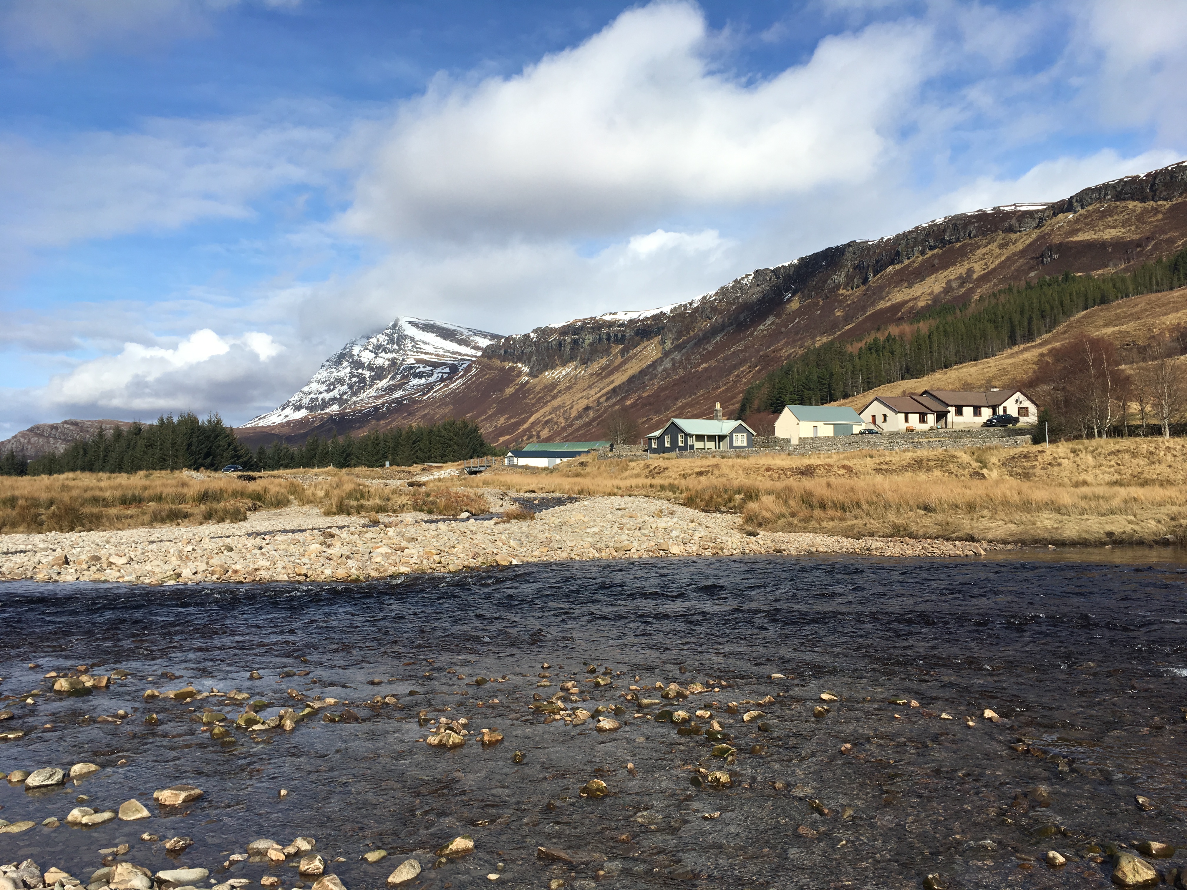 A Scottish landscape with snowy mountains and houses on the shores of a loch