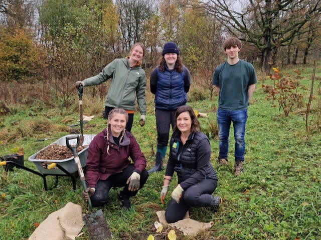 five people in a field with tree planting equipment