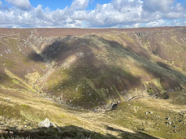 A mountainside with cloud shadows