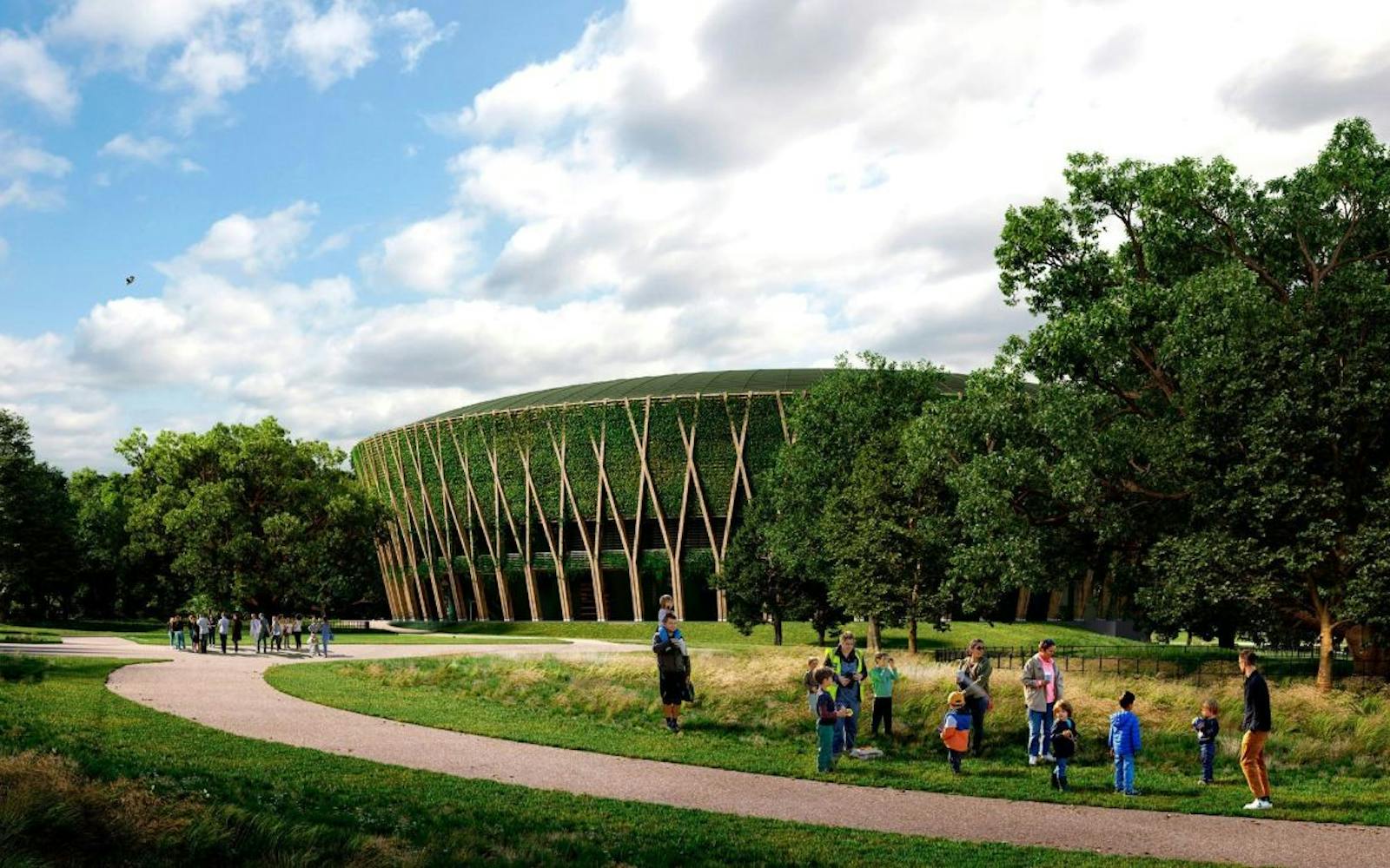 A rendering of a large, circular building surrounded by a park-like setting. The building's exterior is covered in a green wall of vegetation, supported by a striking pattern of light brown, diagonal wooden structural elements that resemble large intersecting branches. A curved, paved pathway cuts through the foreground, which is lined with lush grass and mature trees on both sides. Several small groups of adults and children are visible along the path and in the grassy area, suggesting a public space. The sky is partly cloudy and blue.