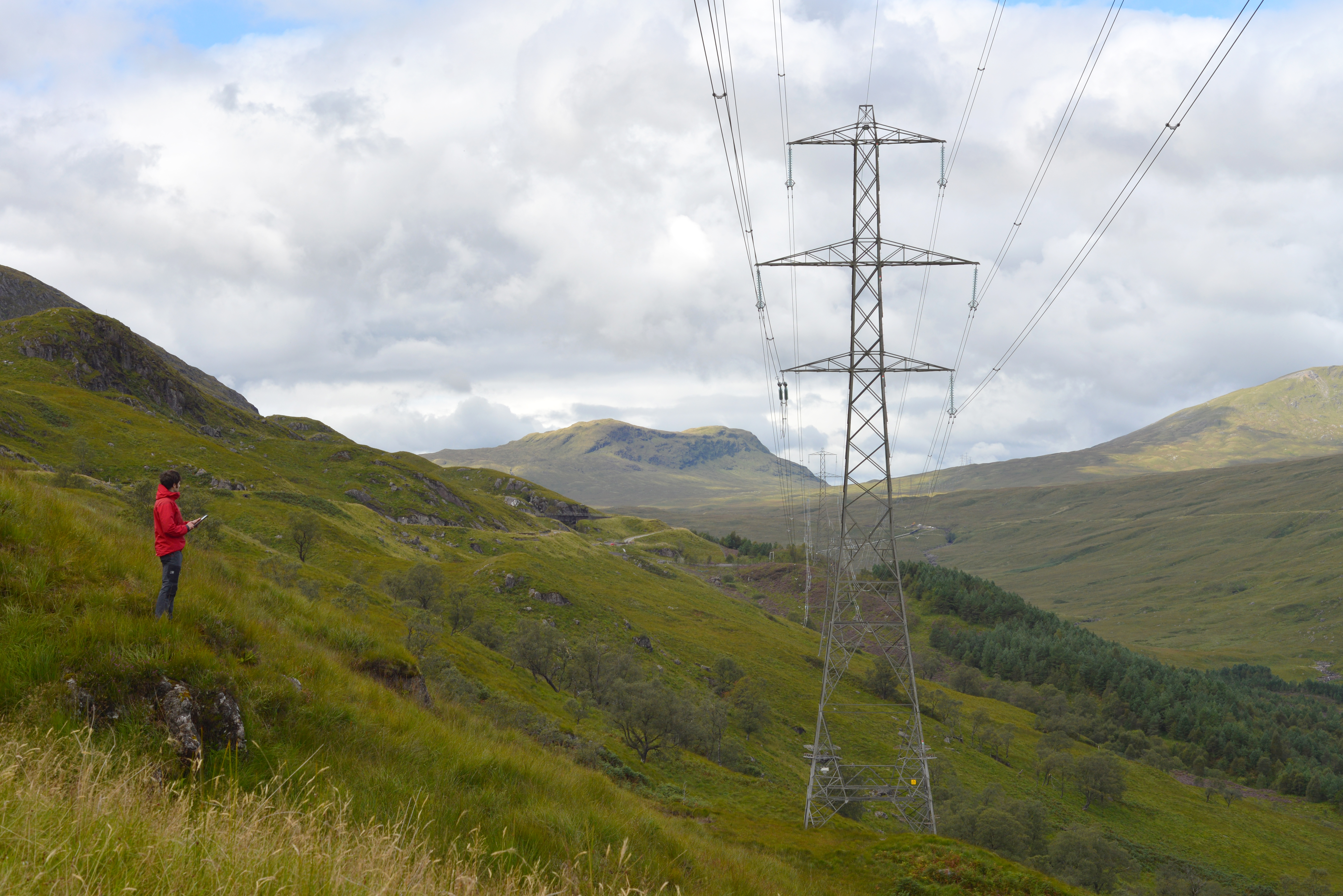 An overhead powerline running through a valley with mountains in the background