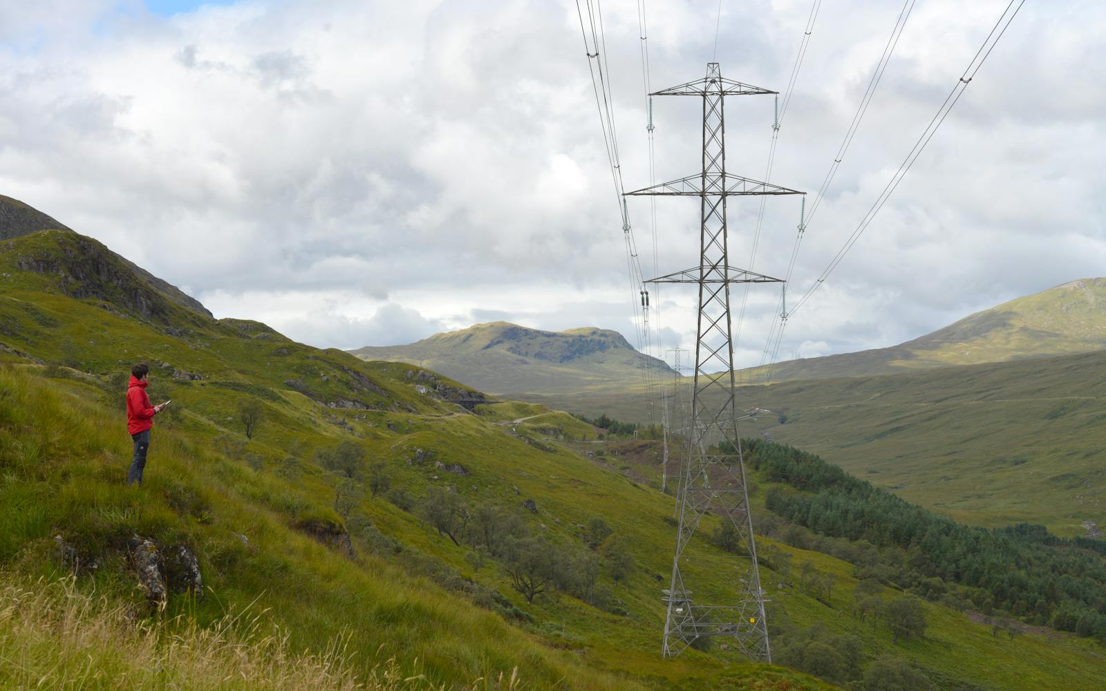 An overhead powerline running through a valley with mountains in the background