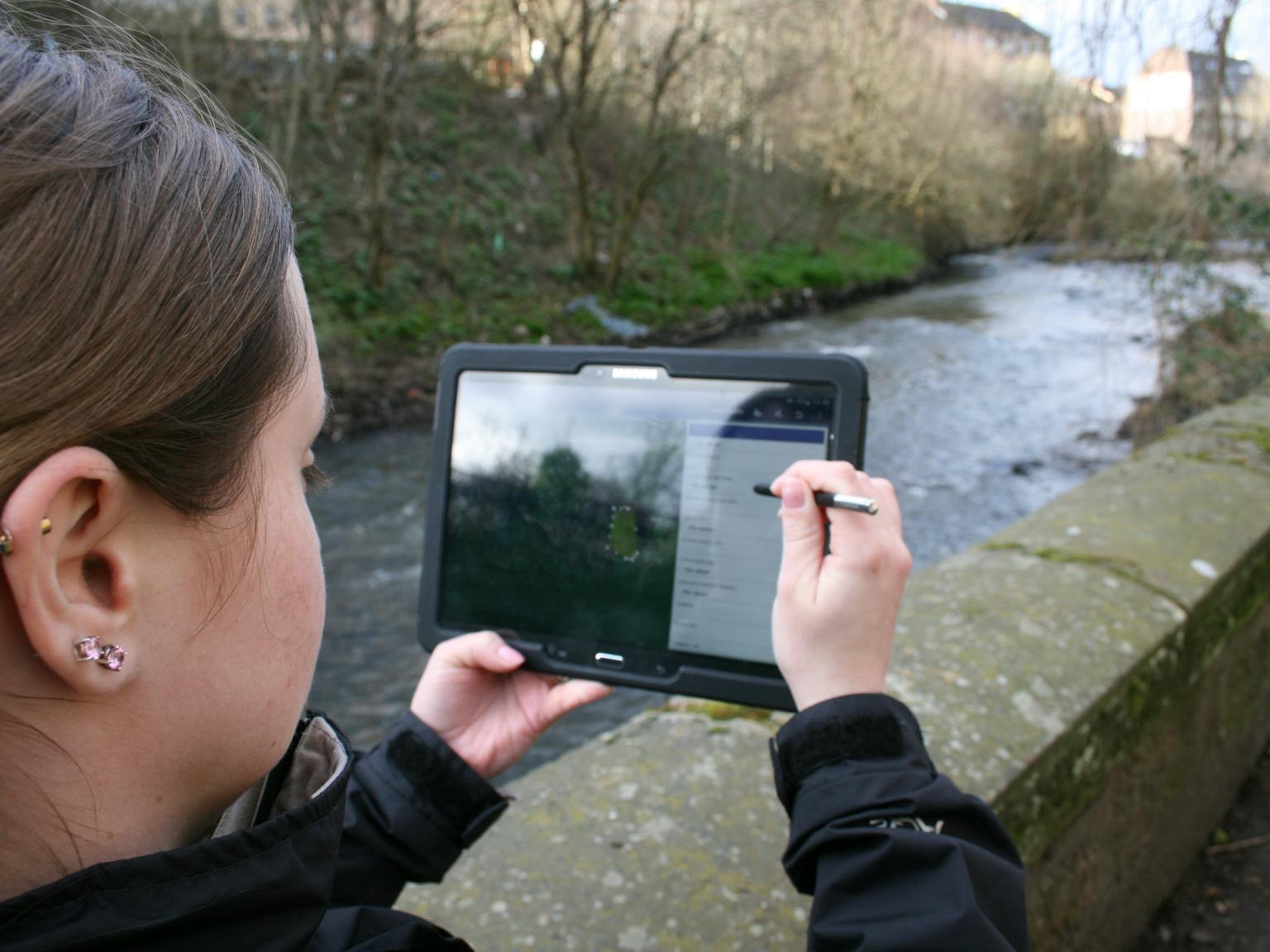 Person using tablet by river