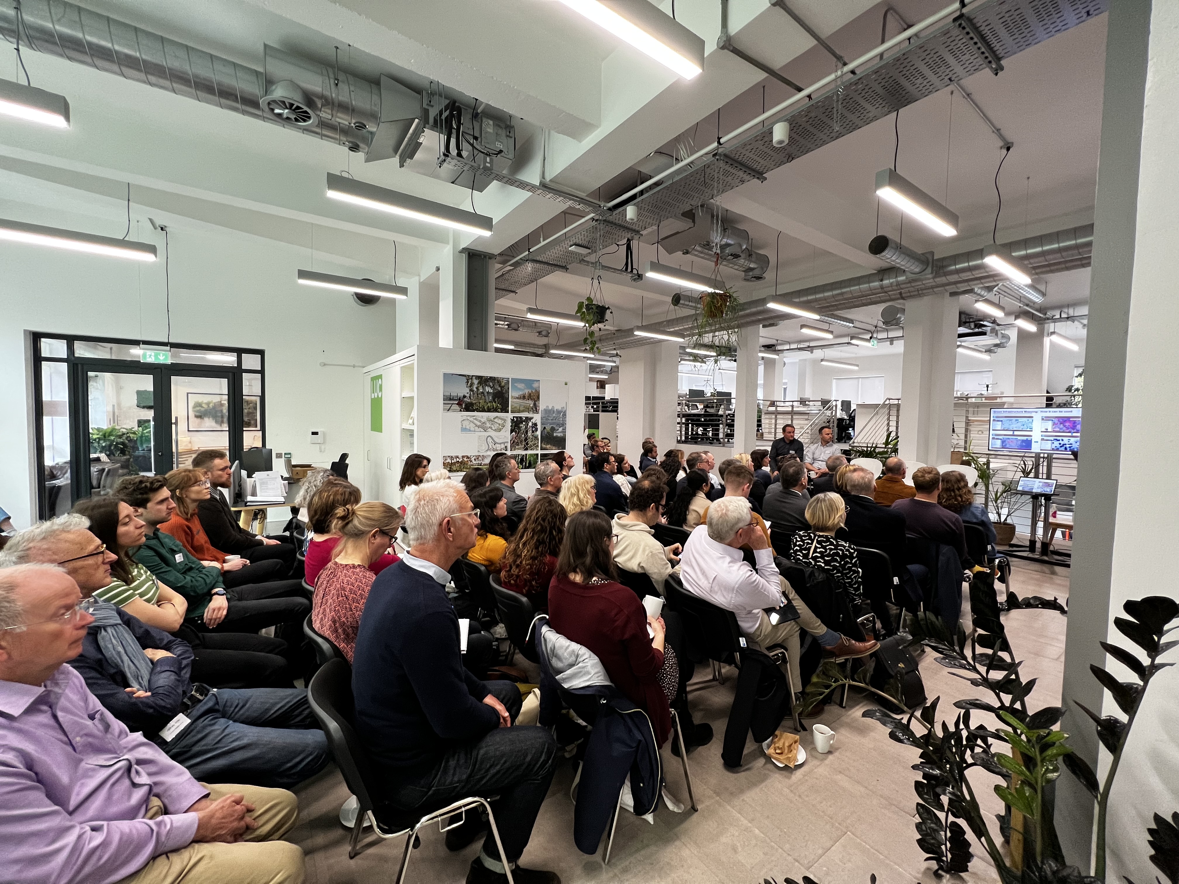 Crowd of people watching a panel discussion comprisng five people