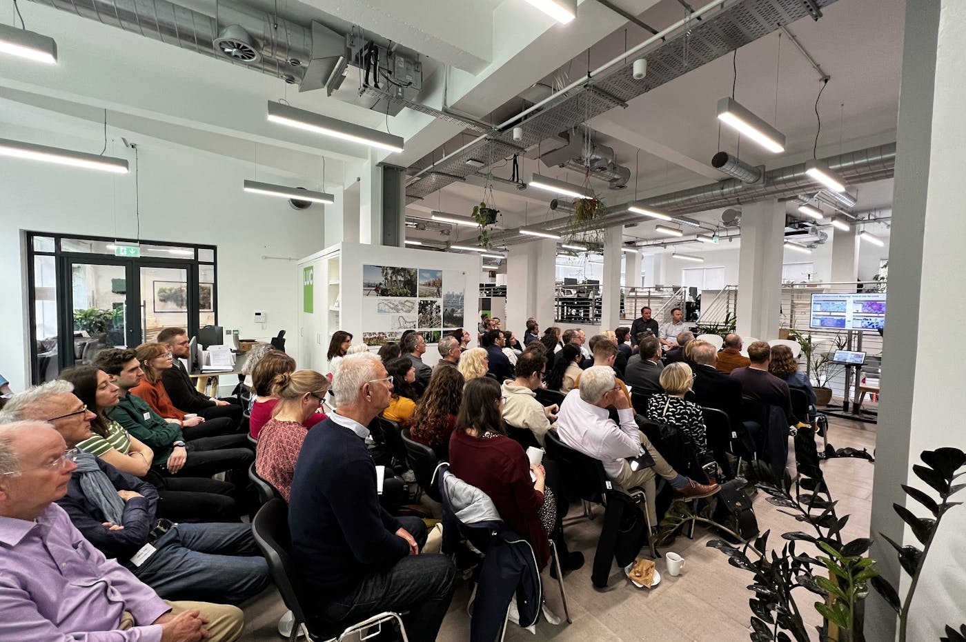 Crowd of people watching a panel discussion comprisng five people