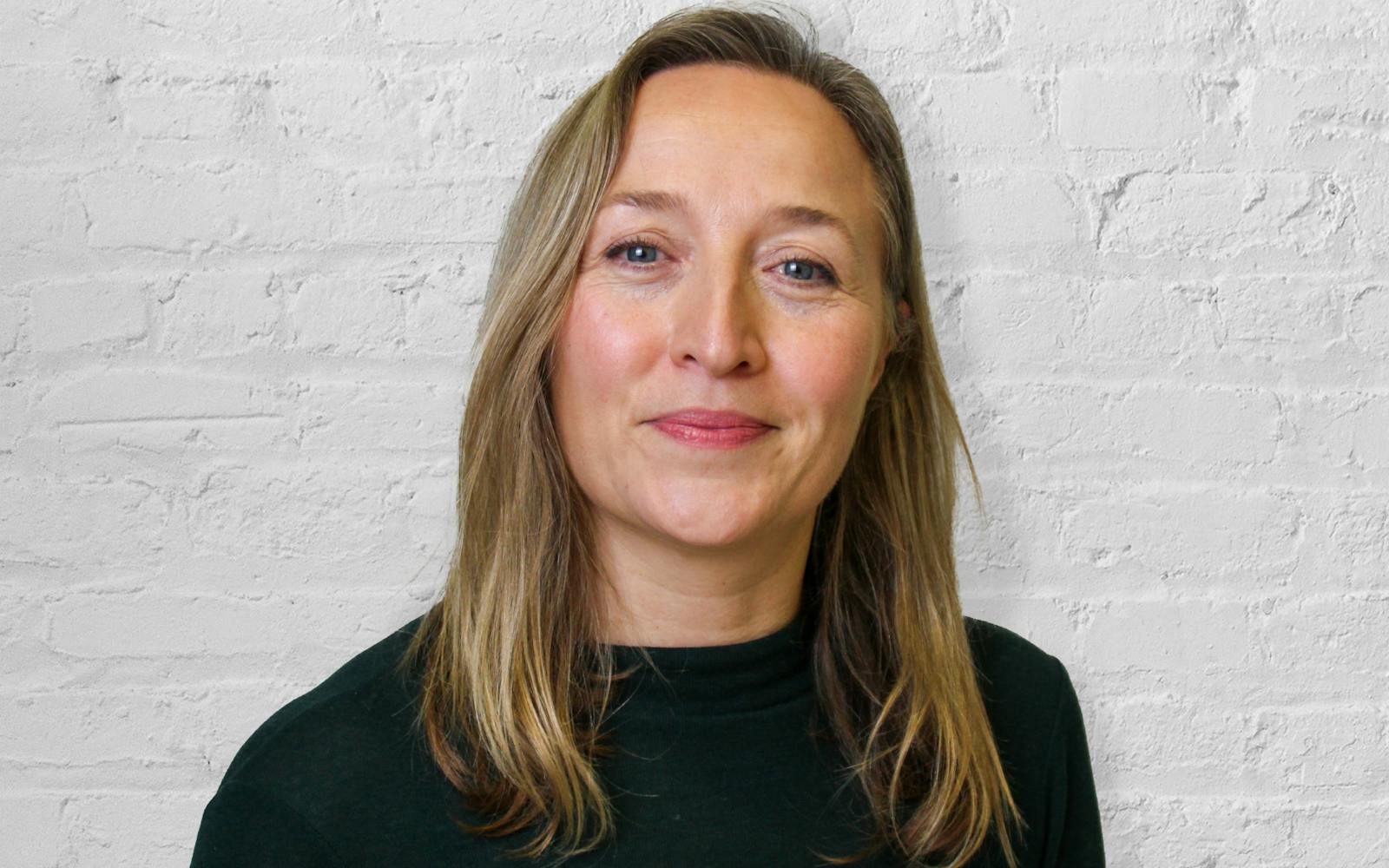 Person smiling in front of brick wall