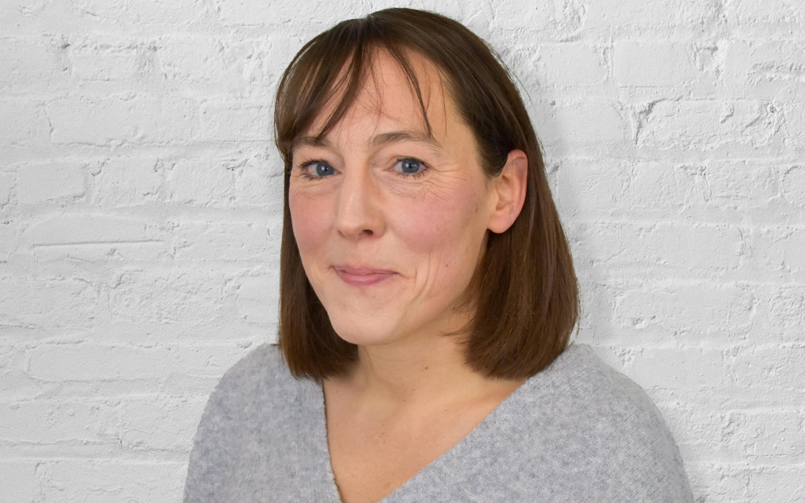 Person smiling in front of white brick wall