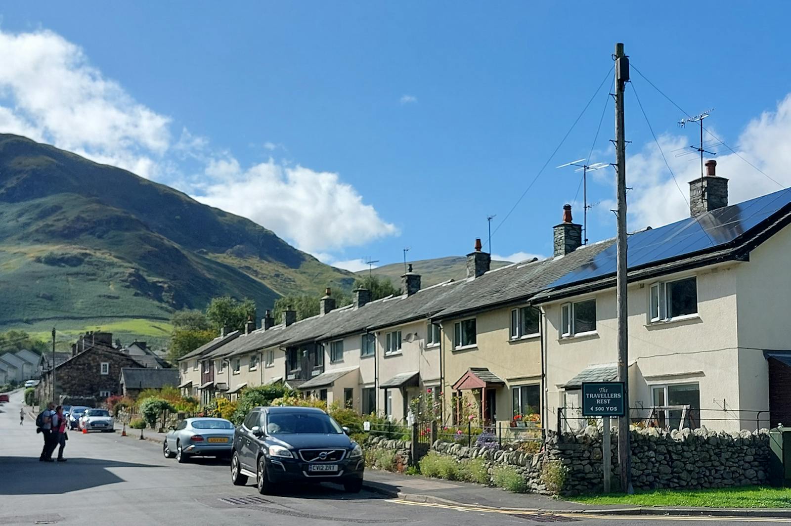 Row of houses on a road with cars and mountain behind