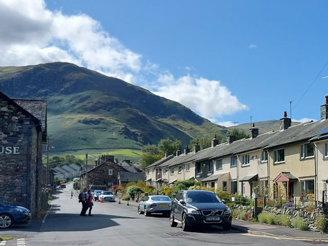 Row of houses on a road with cars and mountain behind