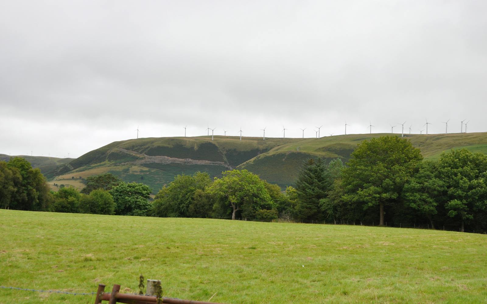 Row of wind turbines on a green hill