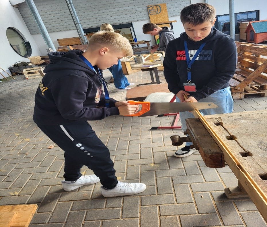 (Zwei Schüler beim Zuschneiden des Holzes)
