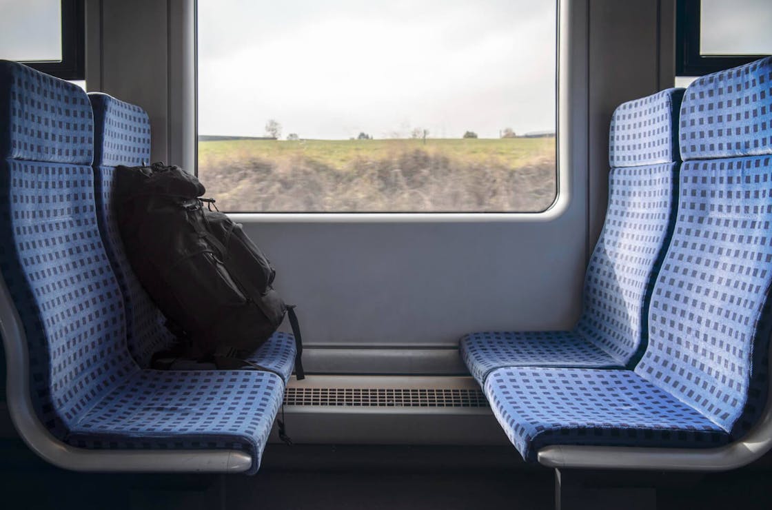 Train seats with blue upholstery and black backpack in a regional train – symbolic image for seat foams in rail vehicles with a focus on fire safety.