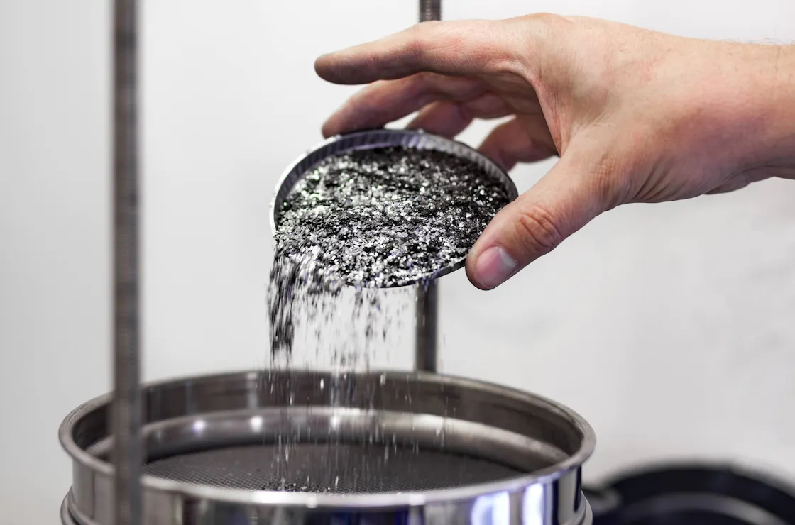 Graphite being poured by hand into a container