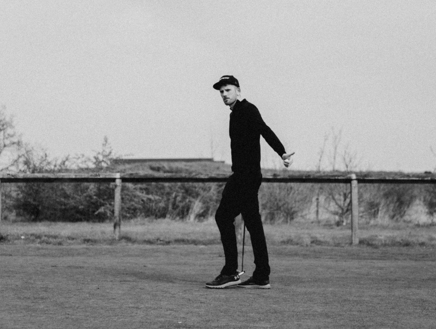 Luke Charles holding a putter giving thumbs up while walking across a putting green