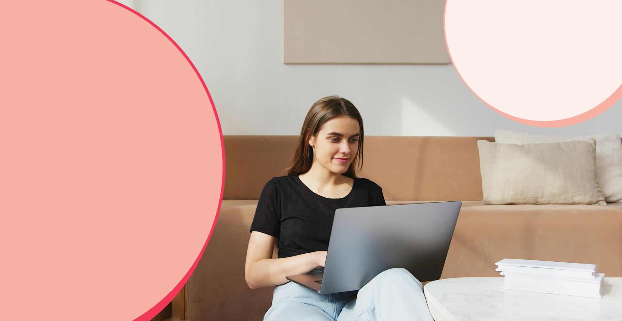 A woman remote working sitting on her lounge floor, laptop on her knee.