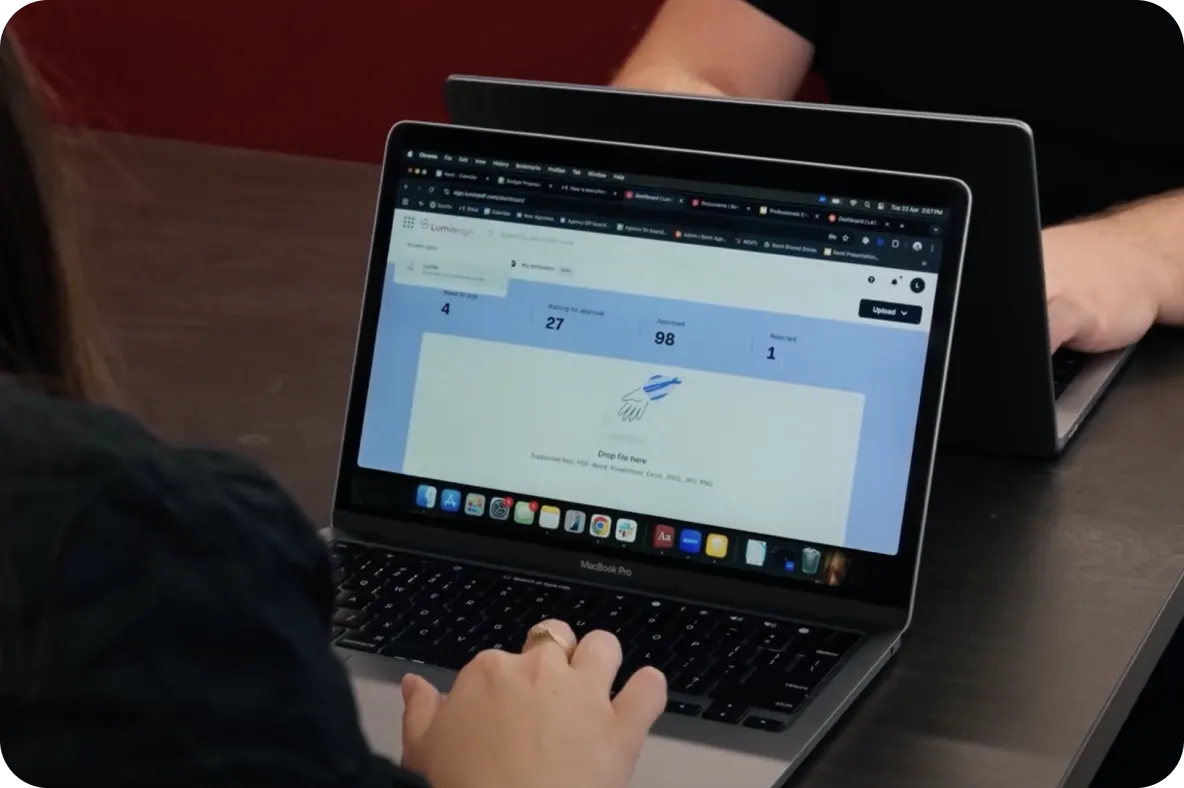 A person using a laptop displaying a document management dashboard with statistics for signed, approved, and rejected files.