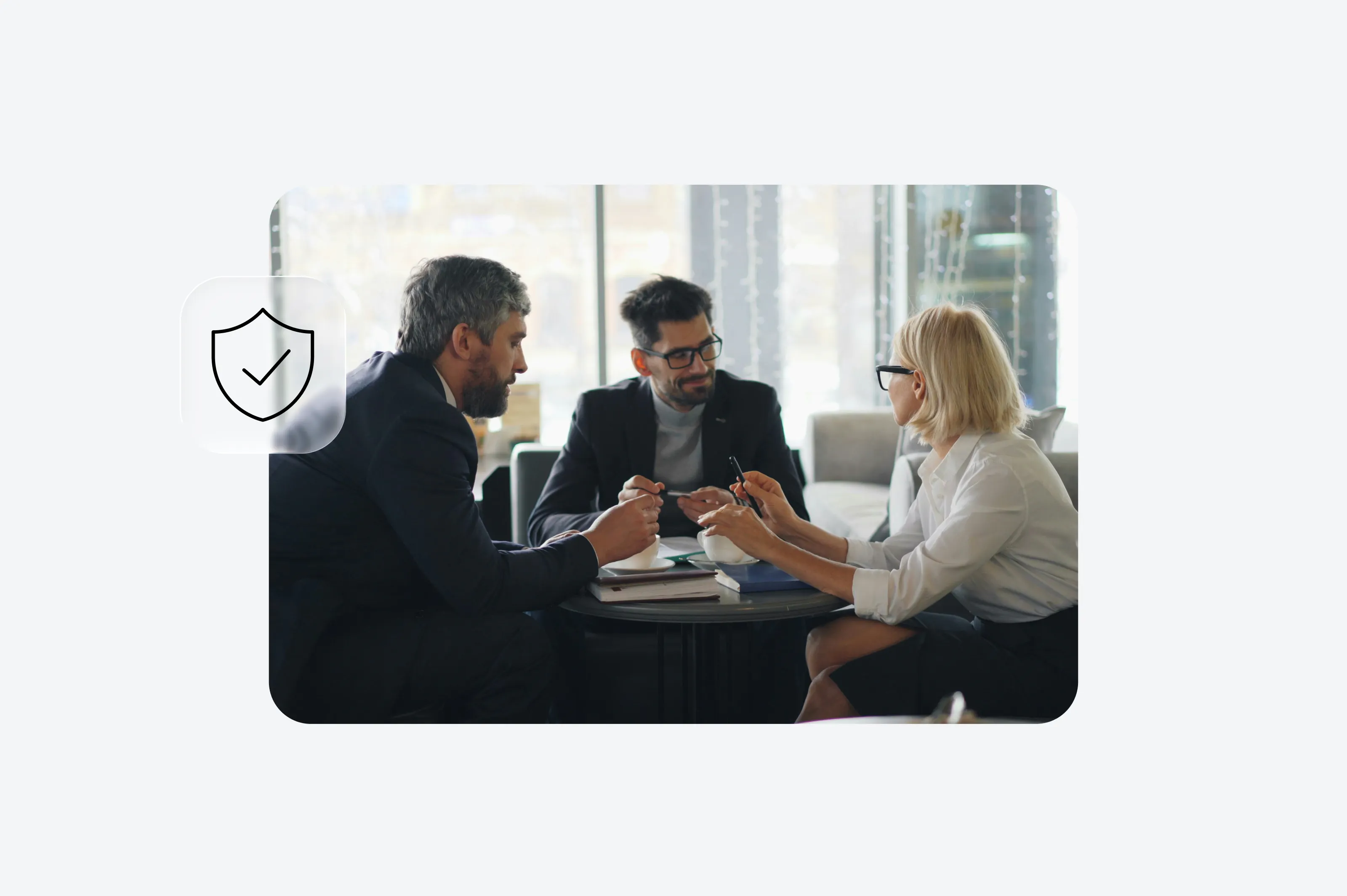 Três profissionais conversando ao redor de uma mesa com um ícone de selo de confiança