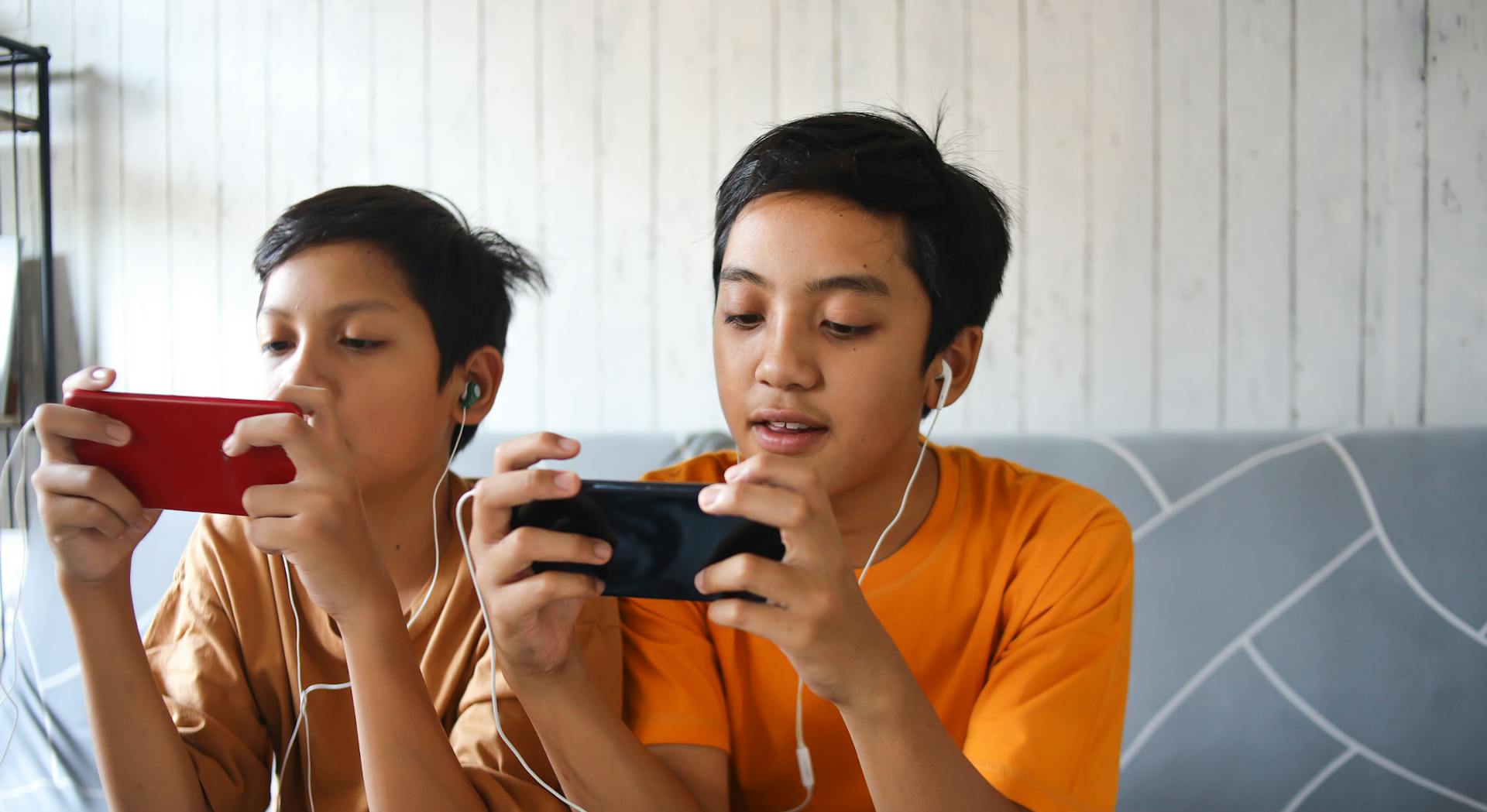 Two kids playing a game on their phones