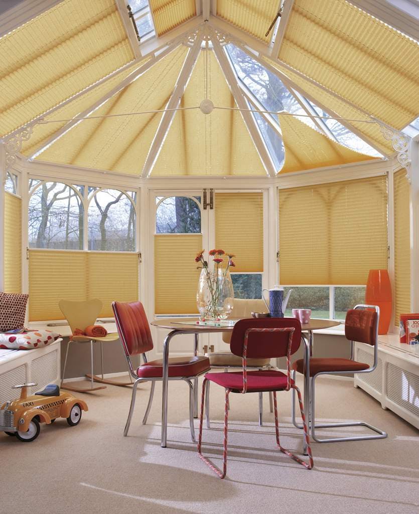 Yellow Plissé shades on conservatory windows in a spacious room