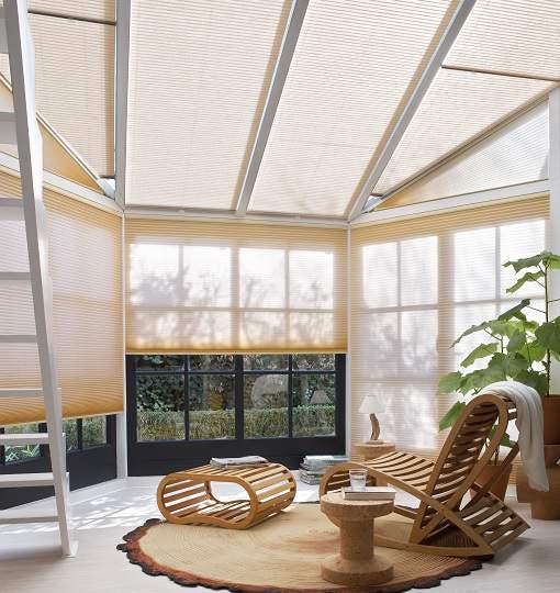 Light yellow Duette® blinds on conservatory windows in a spacious room