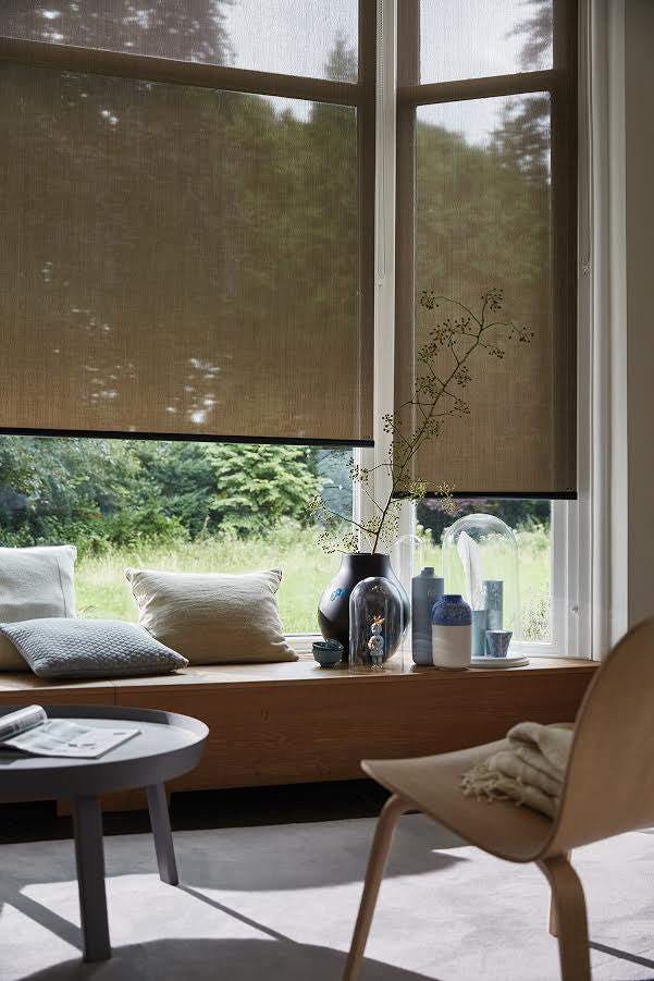 Brown roller blinds on windows in a sunny room