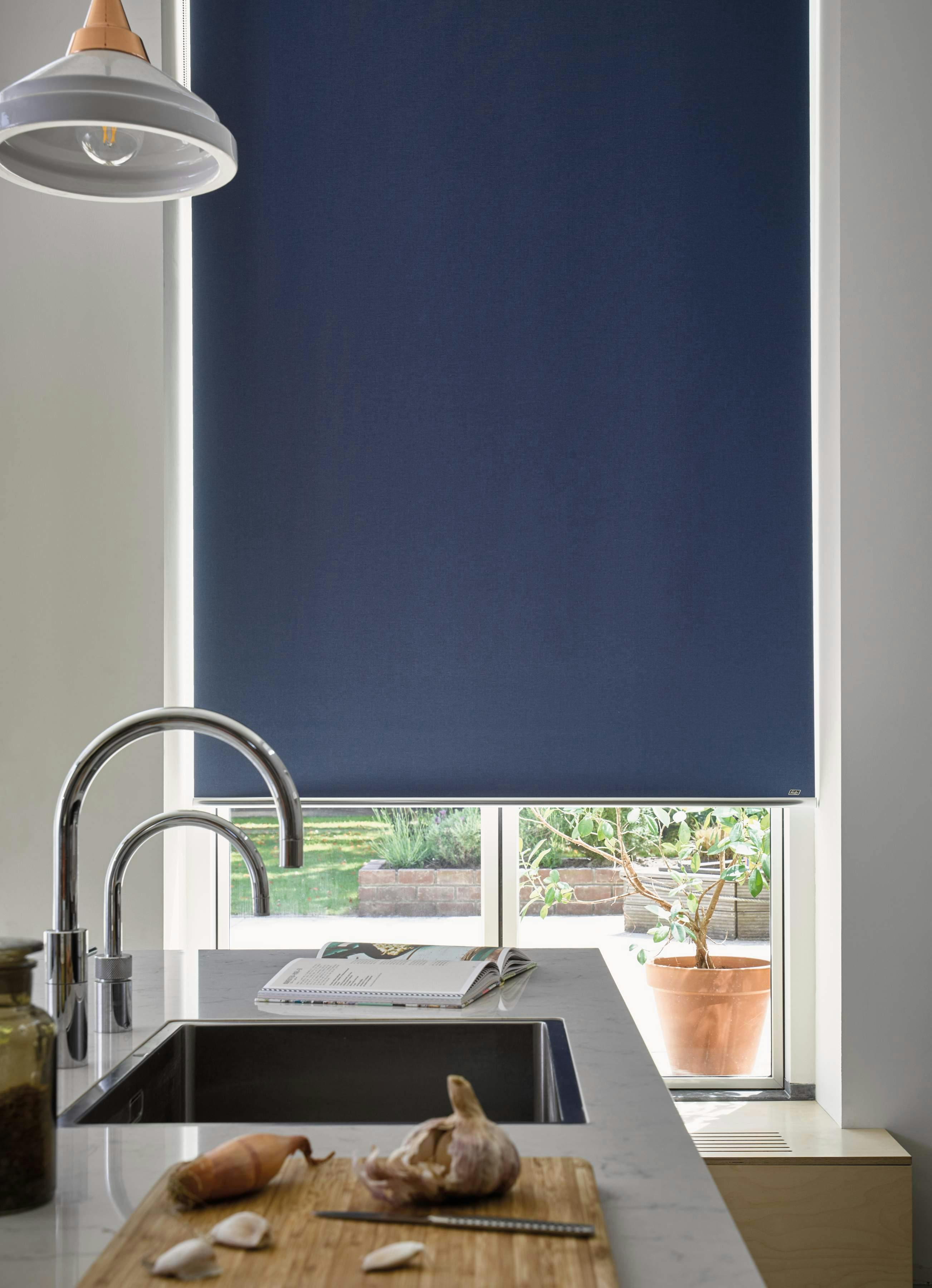 Side view of a kitchen with blue Roller blinds on a window