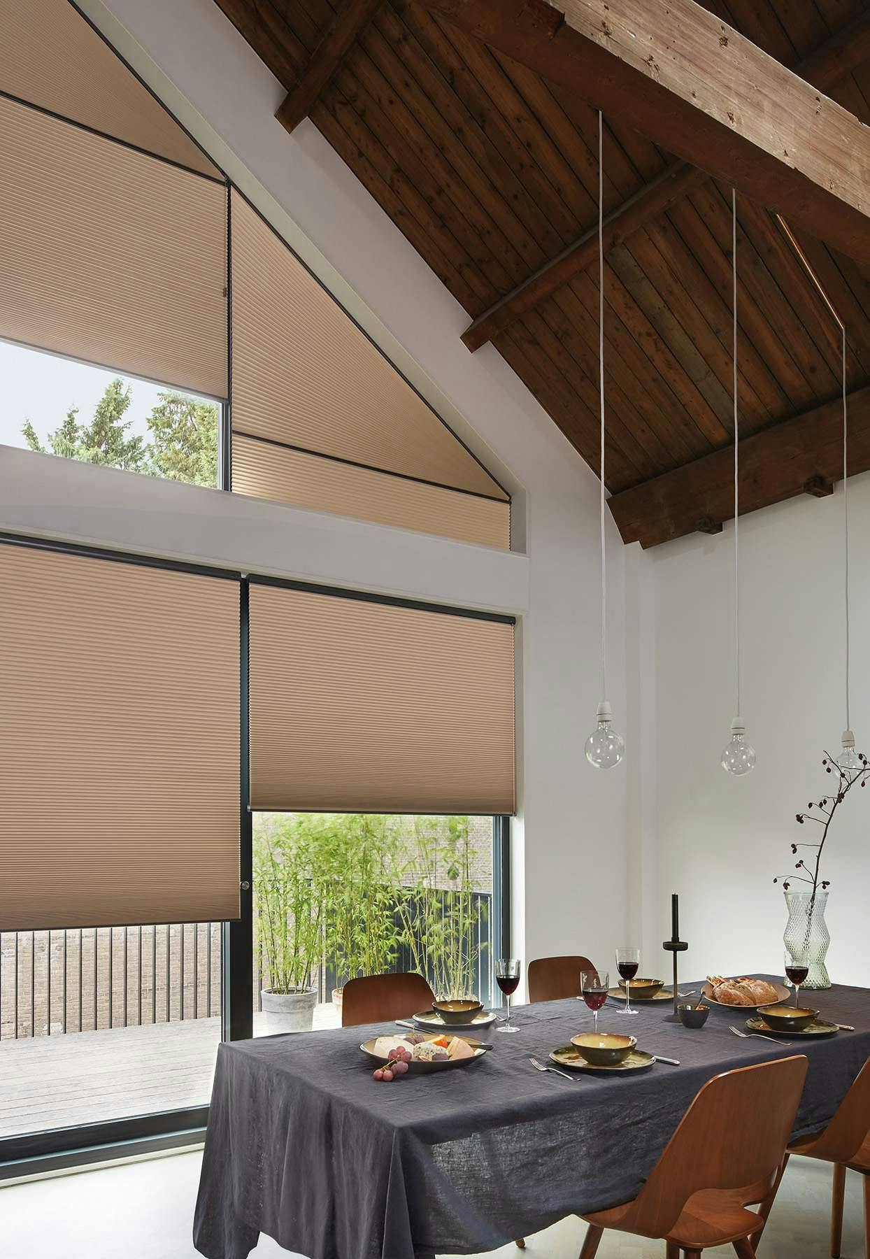 Modern dining room with cream Duette® blinds on windows 
