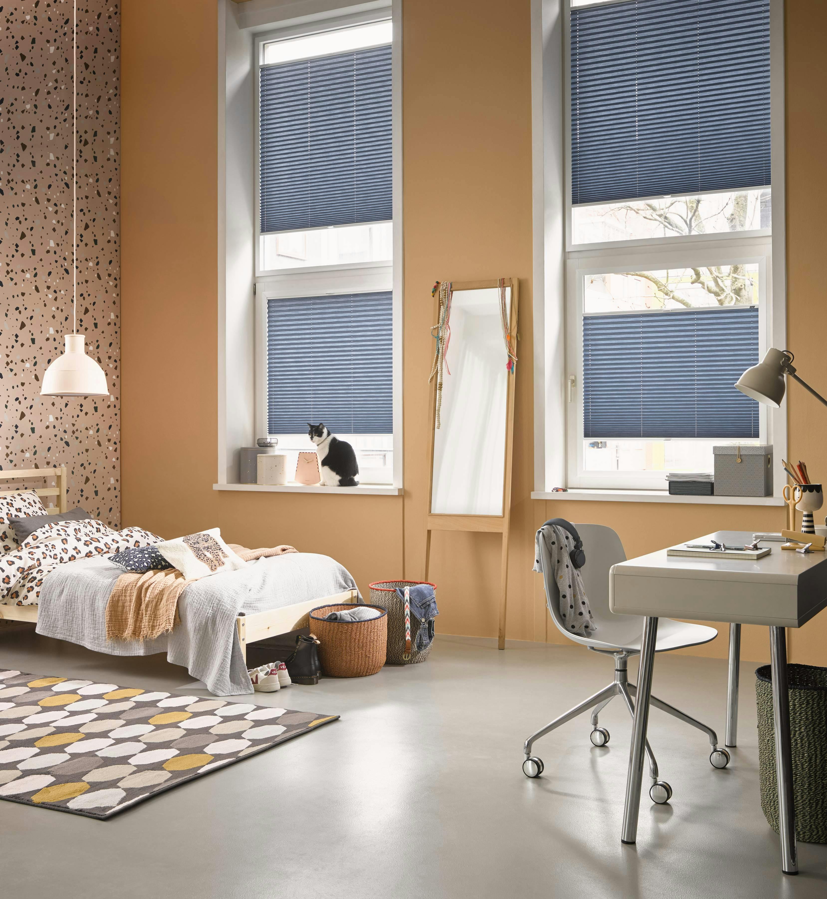 Spacious bedroom with blue Plissé shades on windows