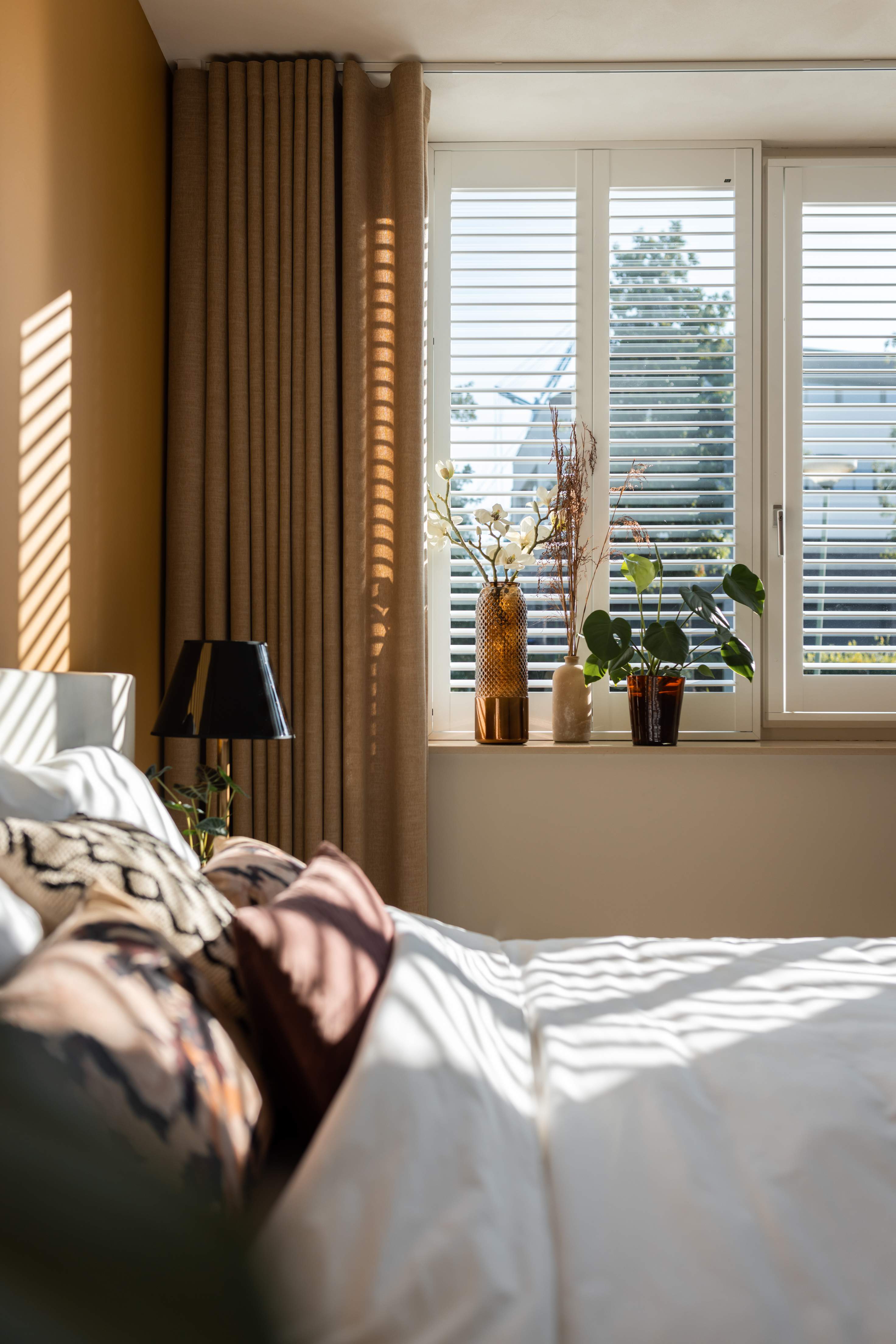 Side view of a light bedroom with white Wood blinds on a window