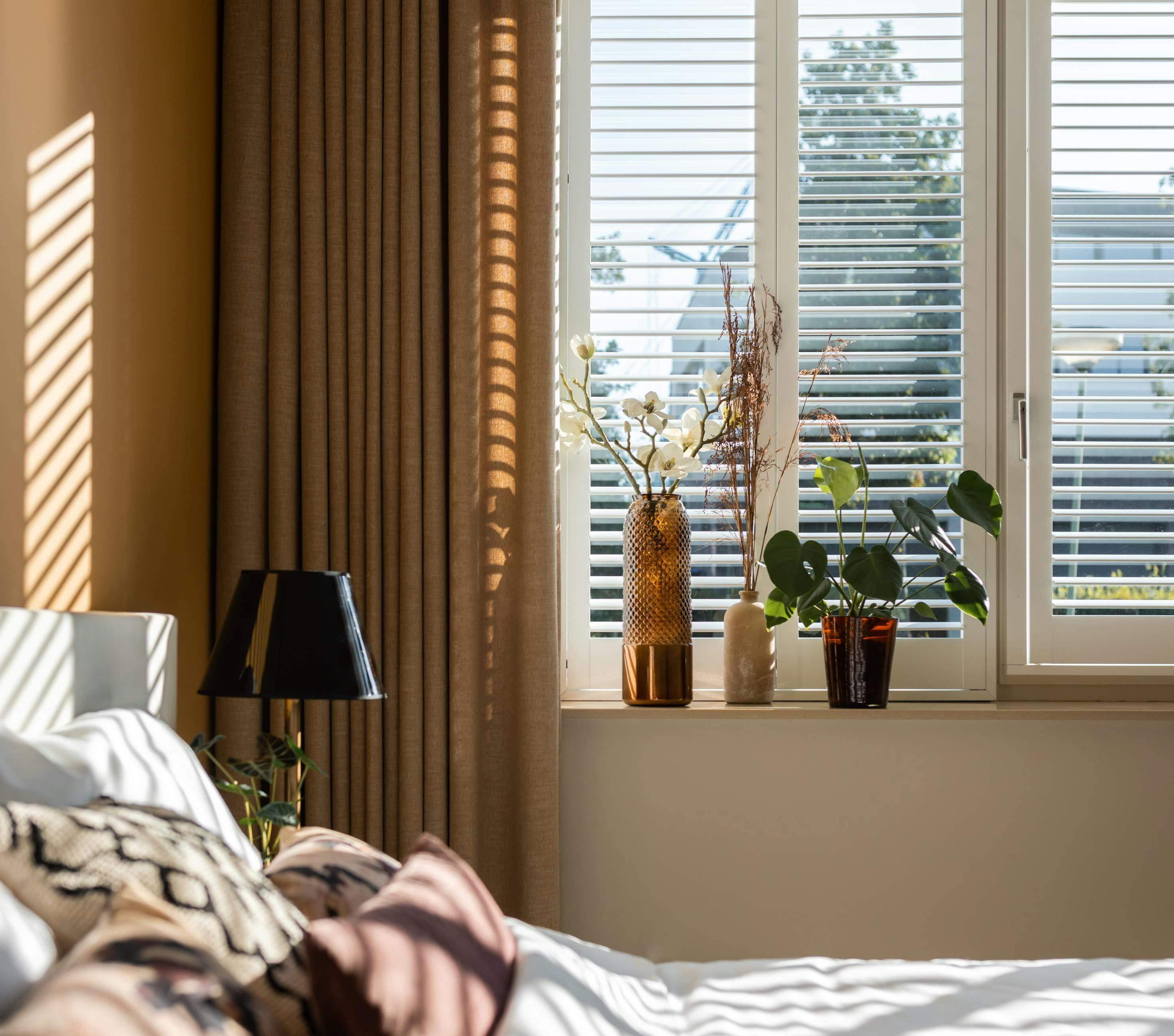 Side view of a light bedroom with white Wood blinds on a window