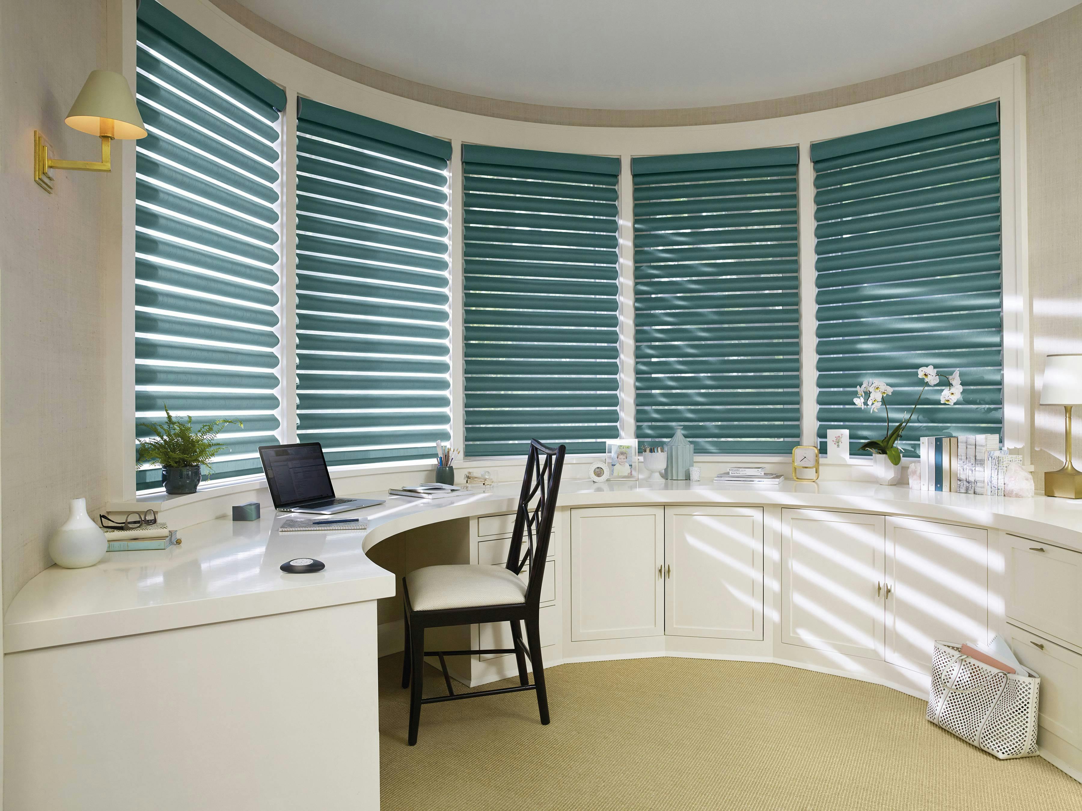 Light home office room with green Pirouette® Shades covering the windows