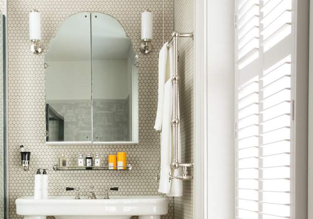 White bathroom with white Wooden blinds displayed on the side on a window